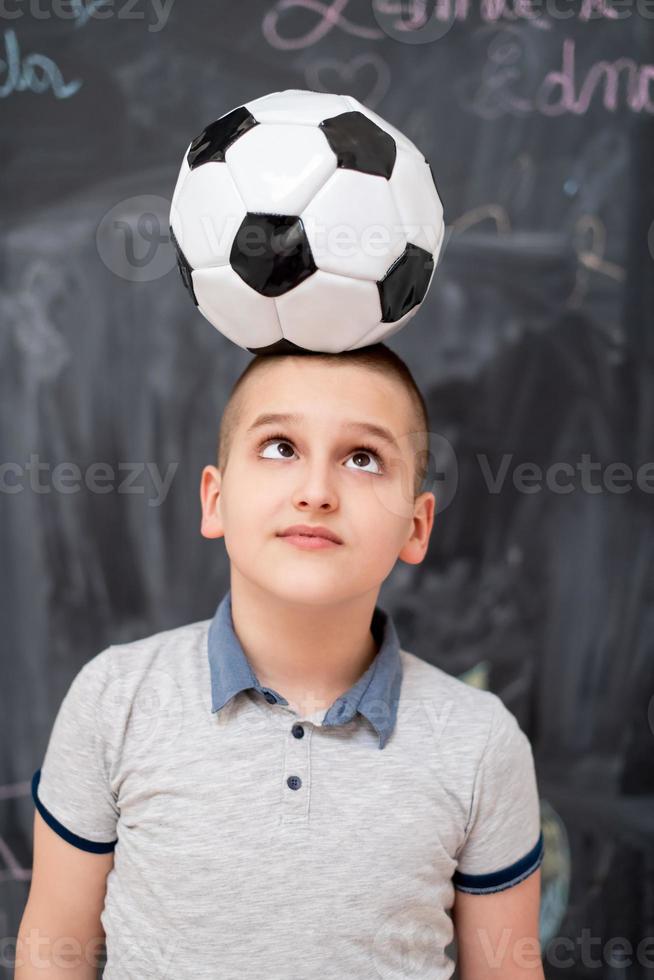 happy boy holding a soccer ball on his head photo