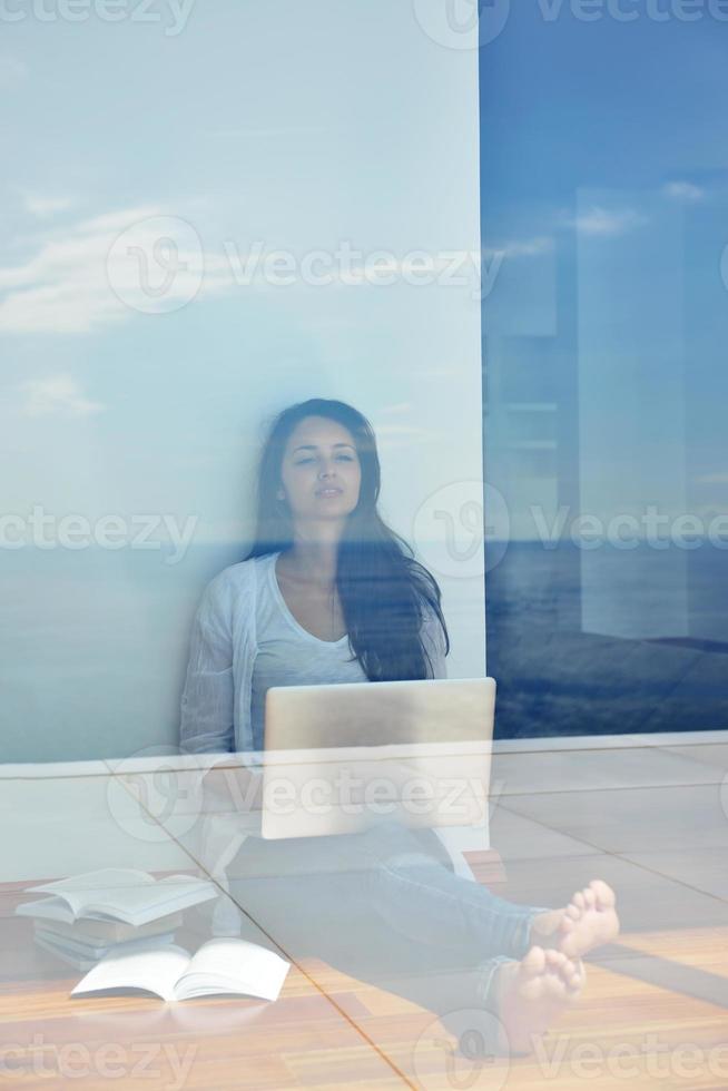 relaxed young woman at home working on laptop computer photo