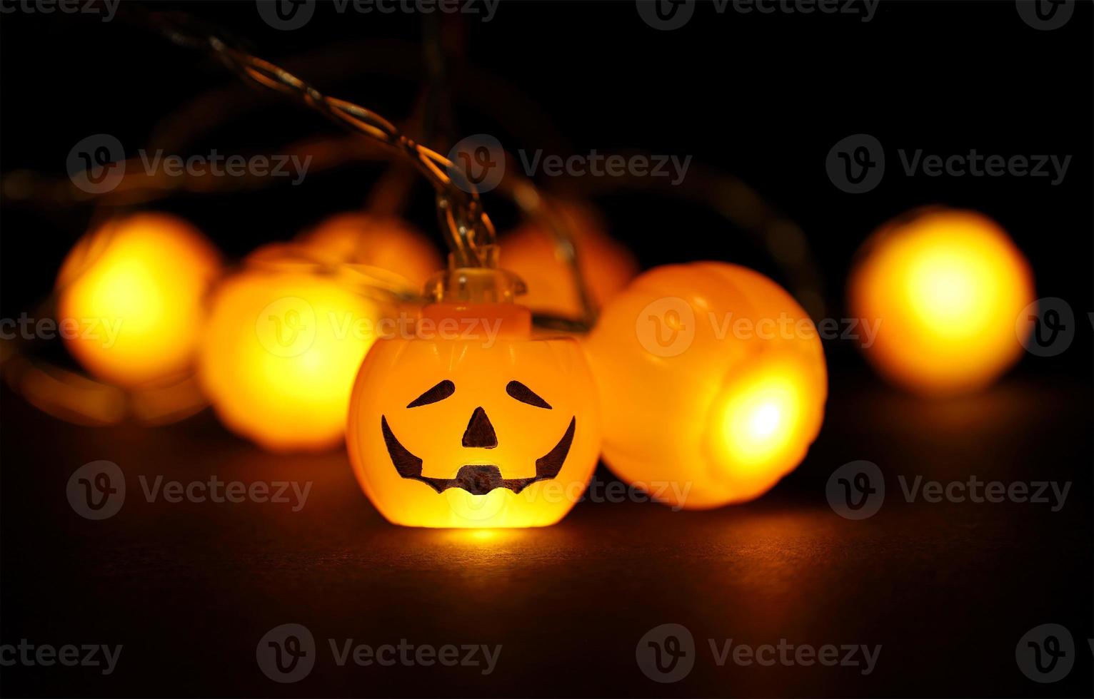 Garland lights of glowing halloween orange pumpkins on black background with copy space. Festive holidays Halloween concept. photo