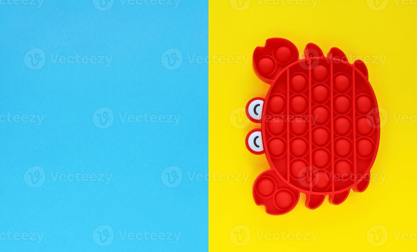 Red crab trendy anti stress sensory silicone bubble fidget toy. Pop it toys. For kids and adults, relaxation, education, inspiration. Holidays summer yellow and blue background. photo