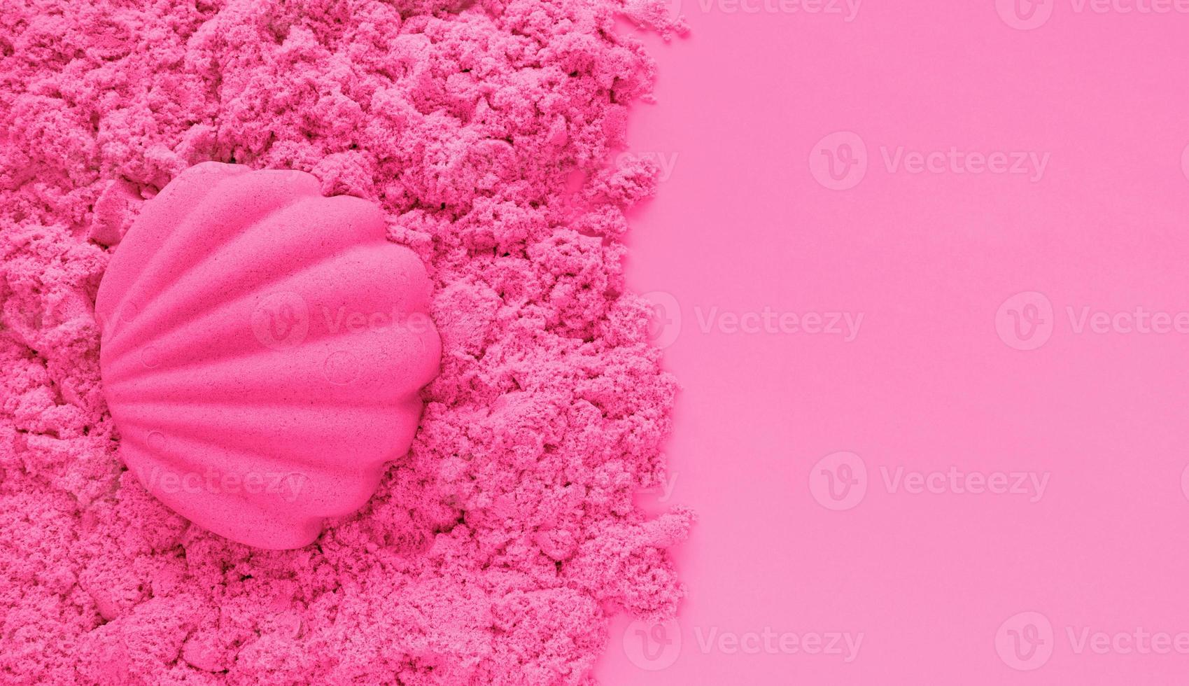 Seashell sand figure made of pink kinetic sand on light pink paper background with copy space. Kids sensory game, development fine motor skills. Leisure and fun time on summer holidays concept. photo