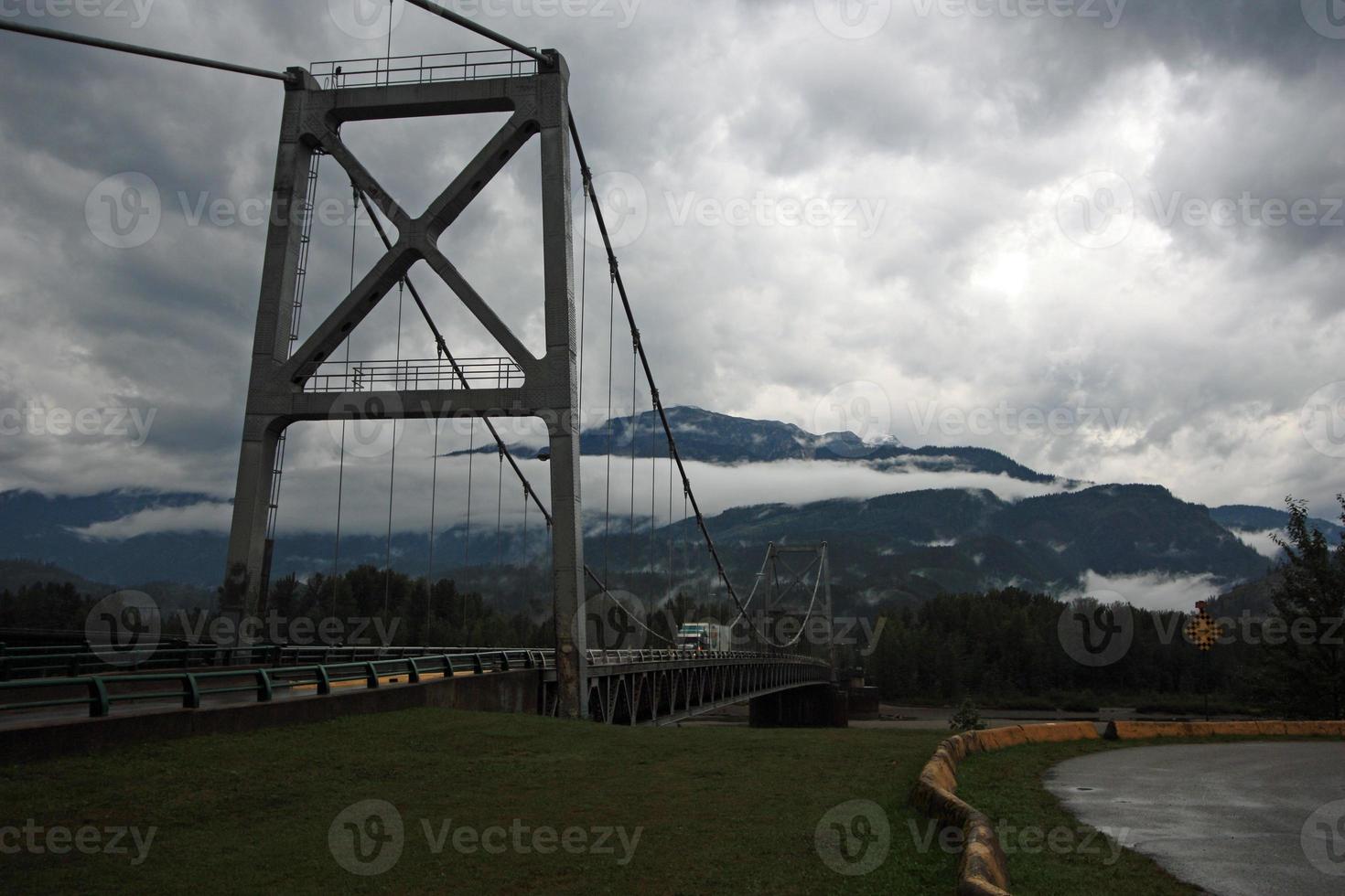 un camión semirremolque en un puente sobre un río a través de una cadena montañosa. foto