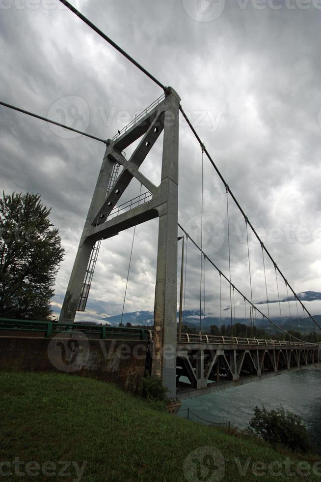A suspension bridge going over a river in the mountains. photo