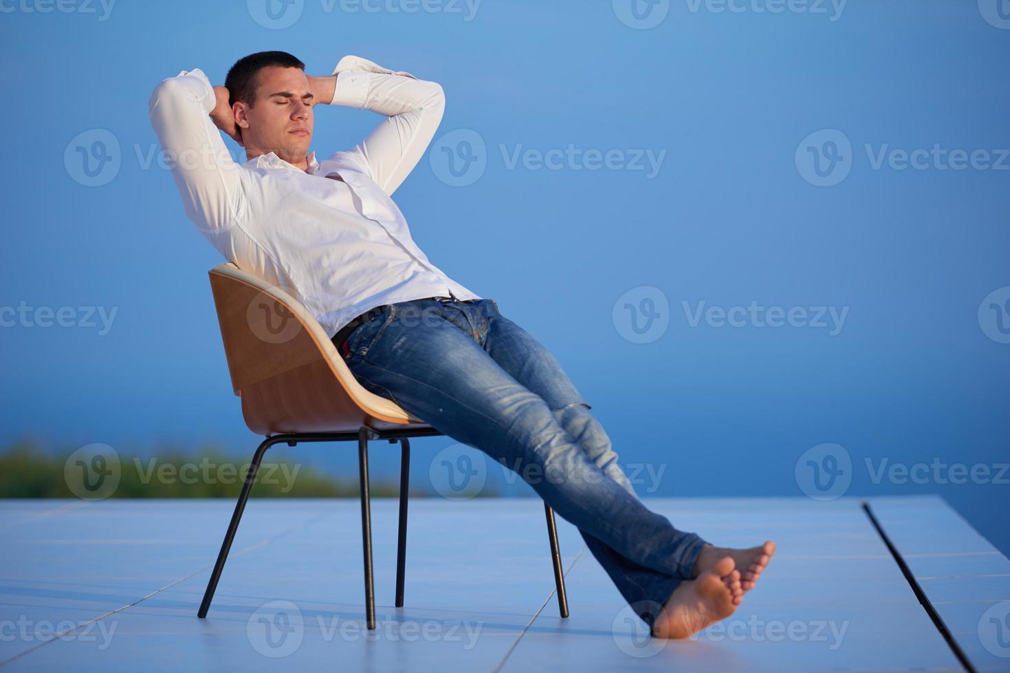 relaxed young man at home on balcony photo