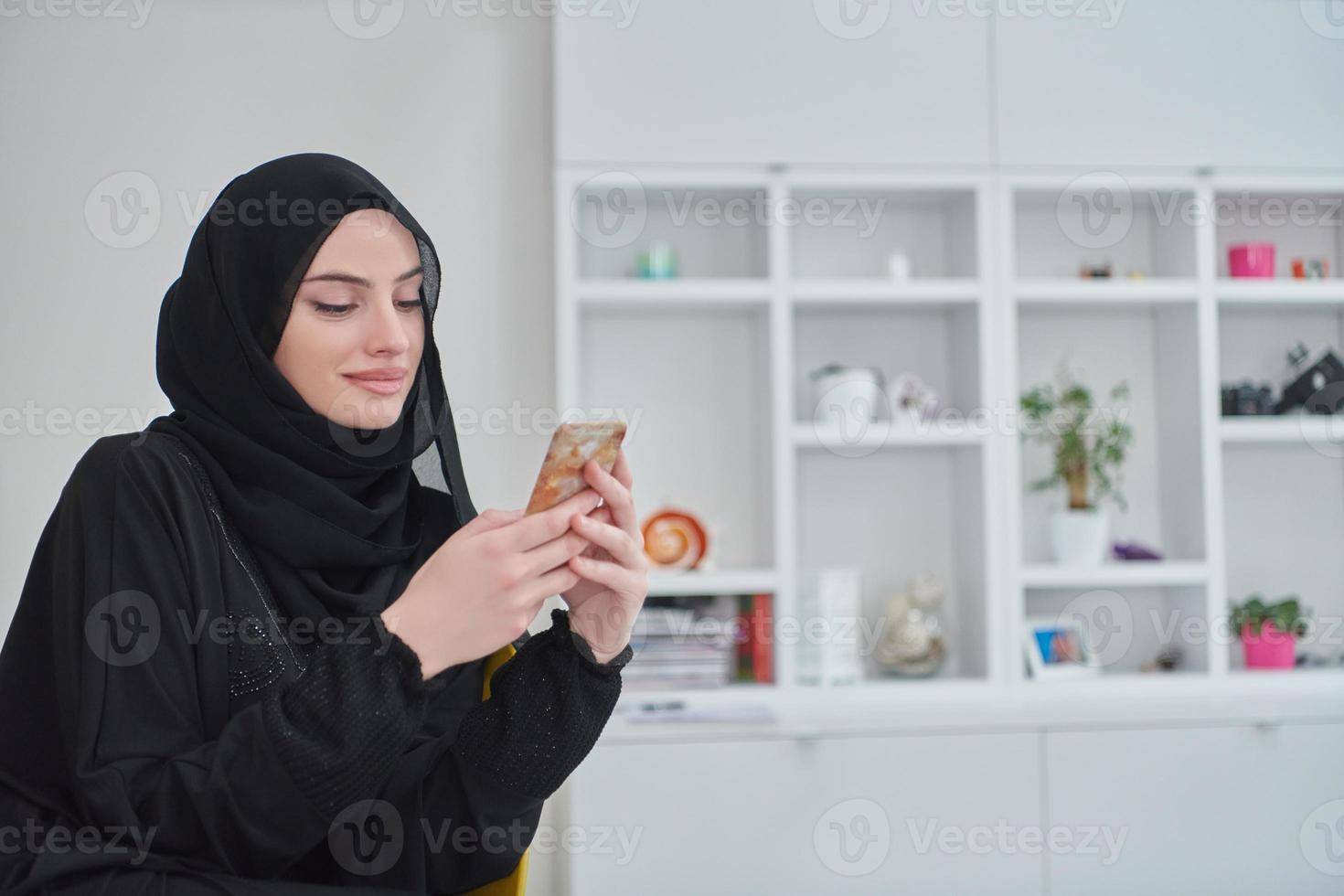 Young muslim woman using smartphone in modern home photo