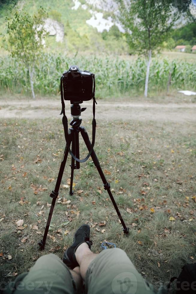 pov photographer in nature taking timelapse photo on pro dslr camera with tripod