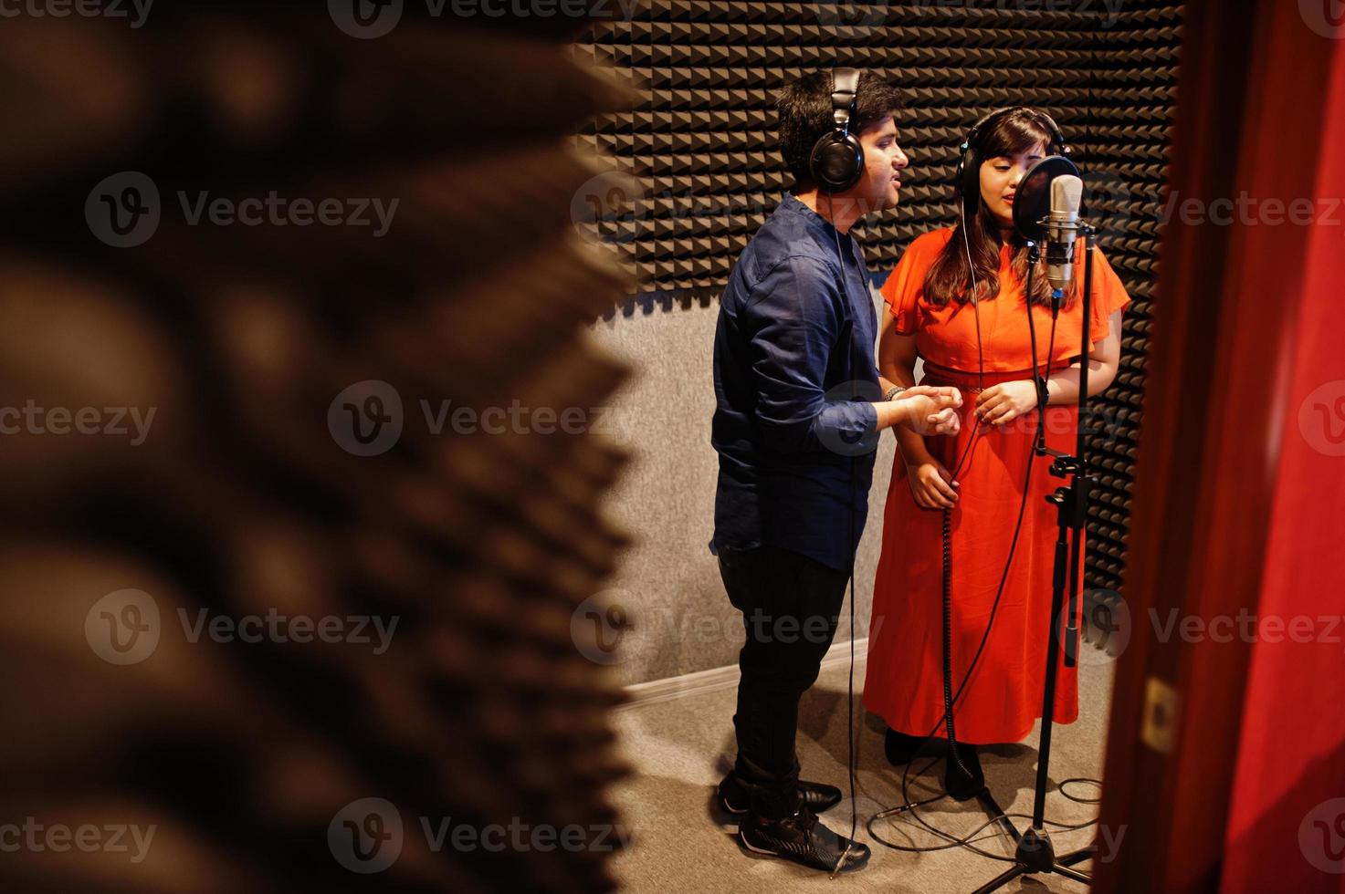 Young asian duet singers with microphone recording song in record music studio. photo