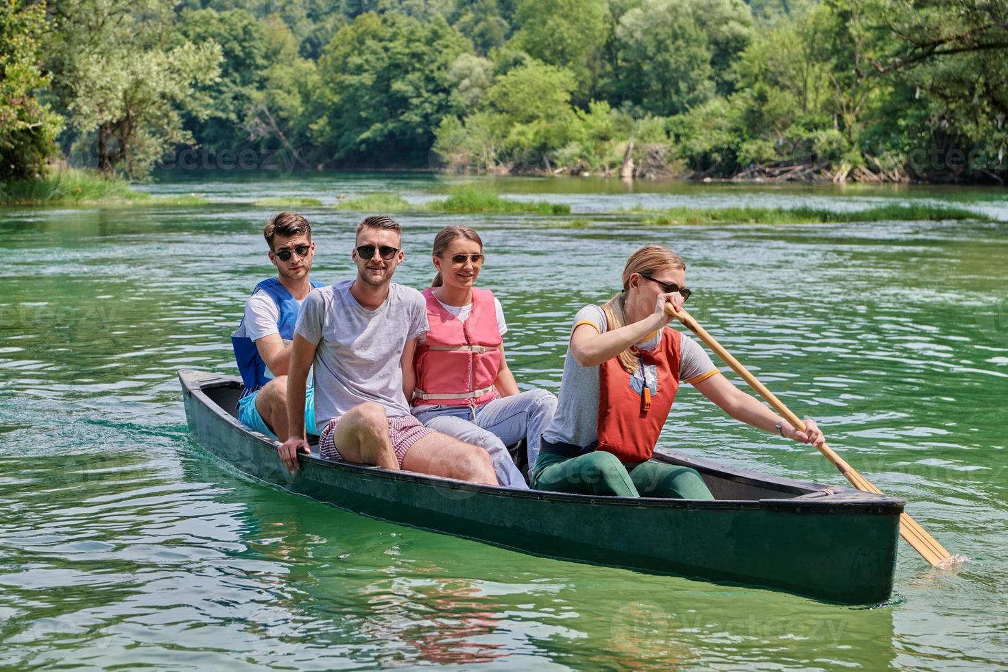 Group adventurous explorer friends are canoeing in a wild river photo