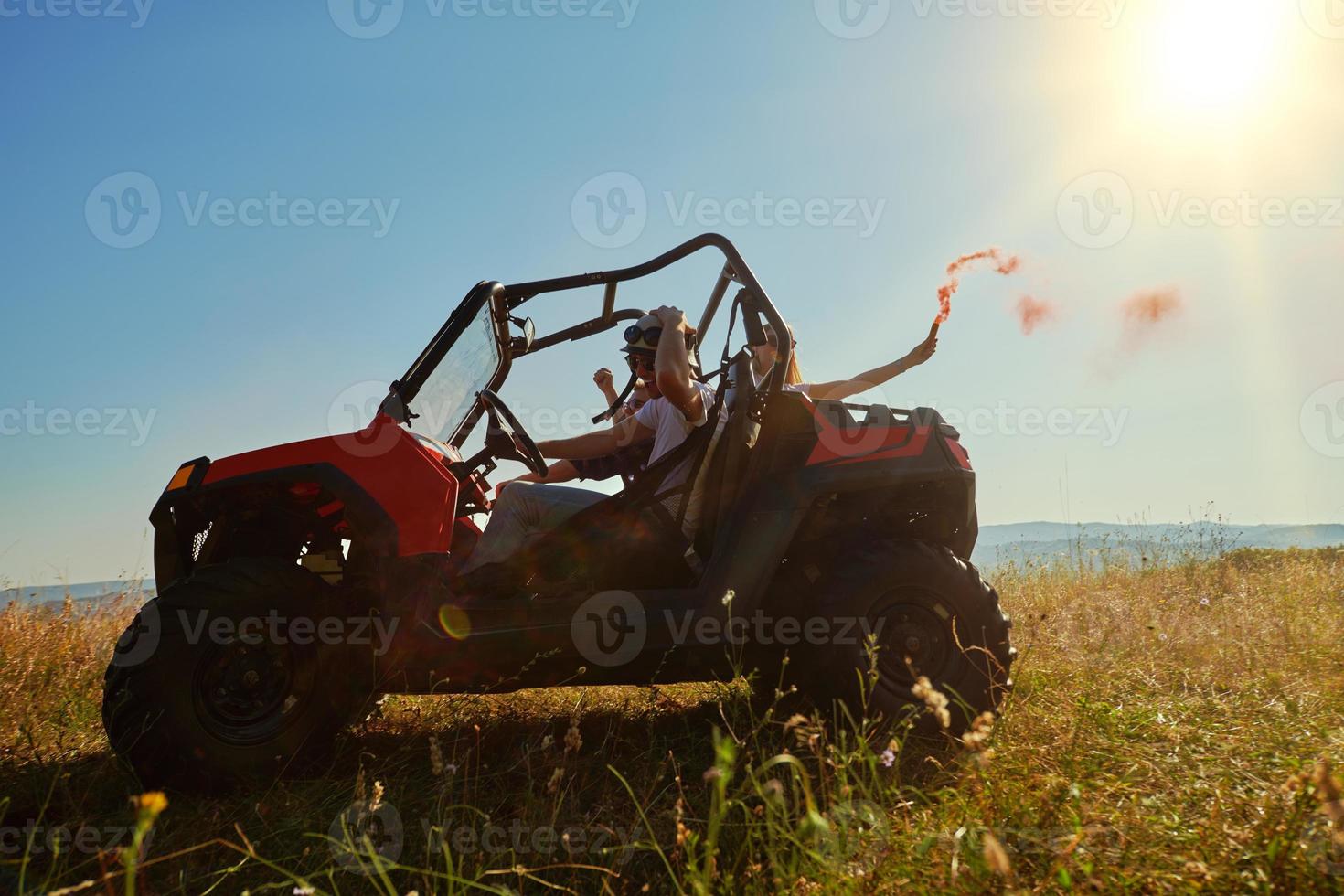 excited people having fun enjoying beautiful sunny day holding colorful torches while driving a off road buggy car photo