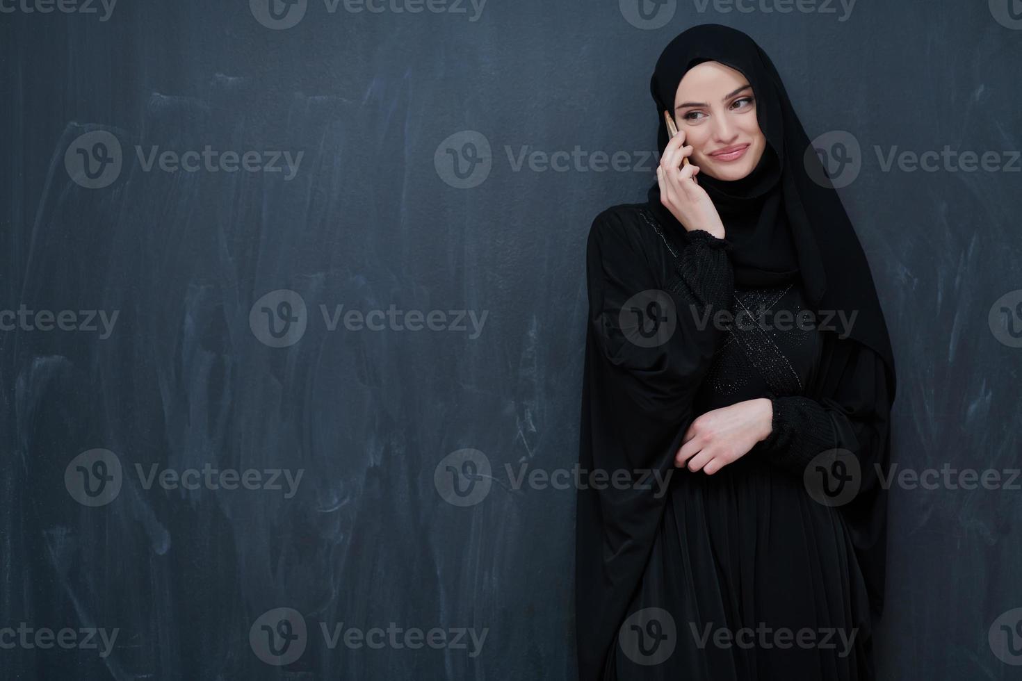 Young muslim businesswoman in traditional clothes or abaya using smartphone photo