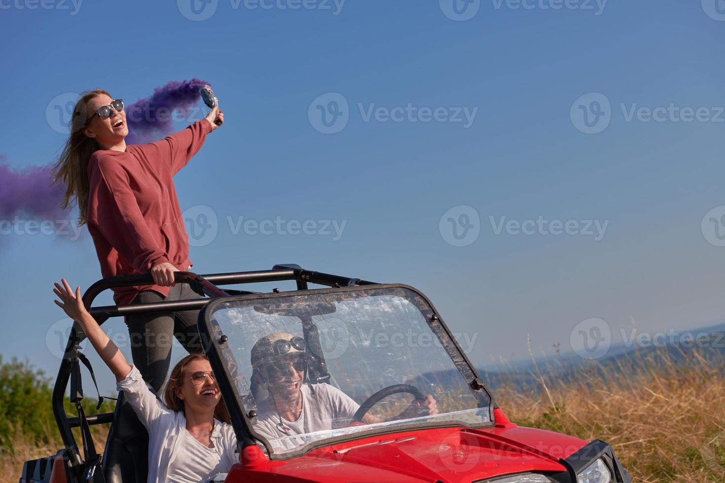 excited people having fun enjoying beautiful sunny day holding colorful torches while driving a off road buggy car photo