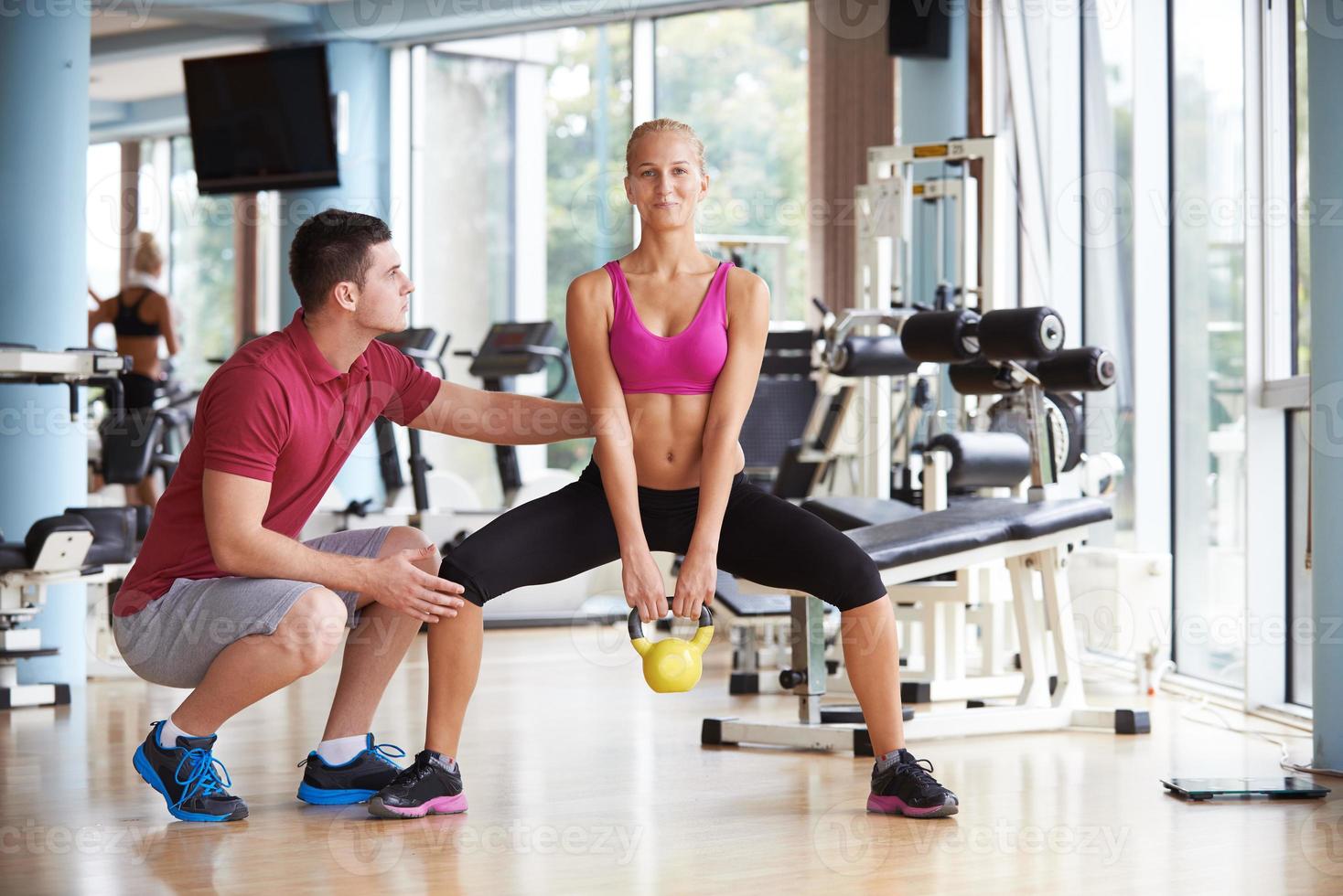 joven mujer deportiva con entrenador ejercicio levantamiento de pesas foto