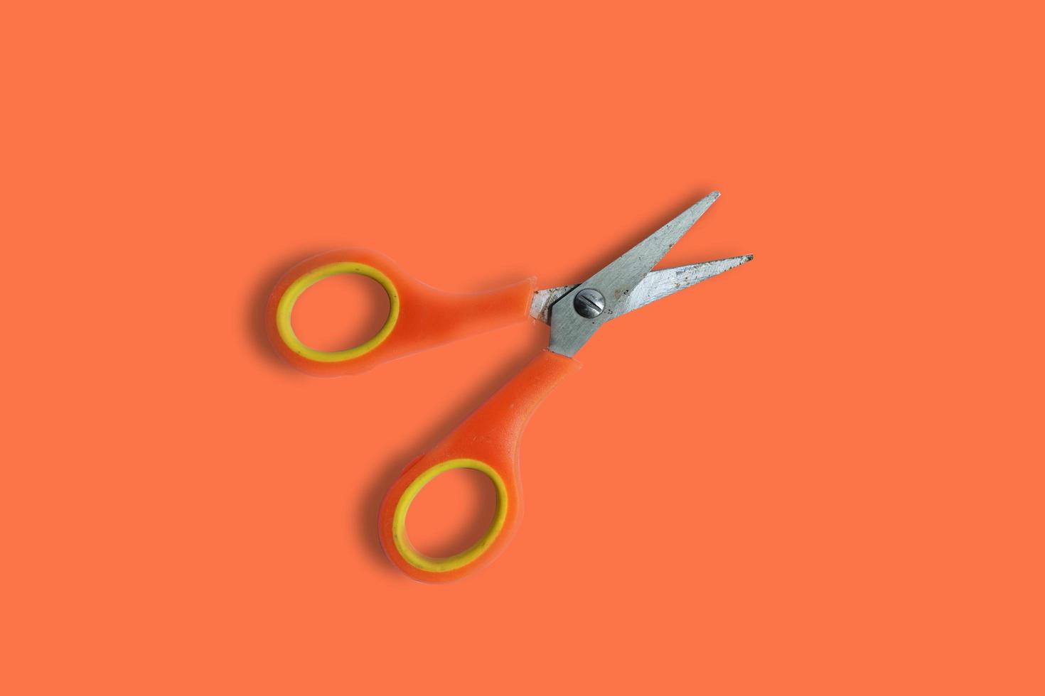 orange aluminum scissors top view on plain orange background photo