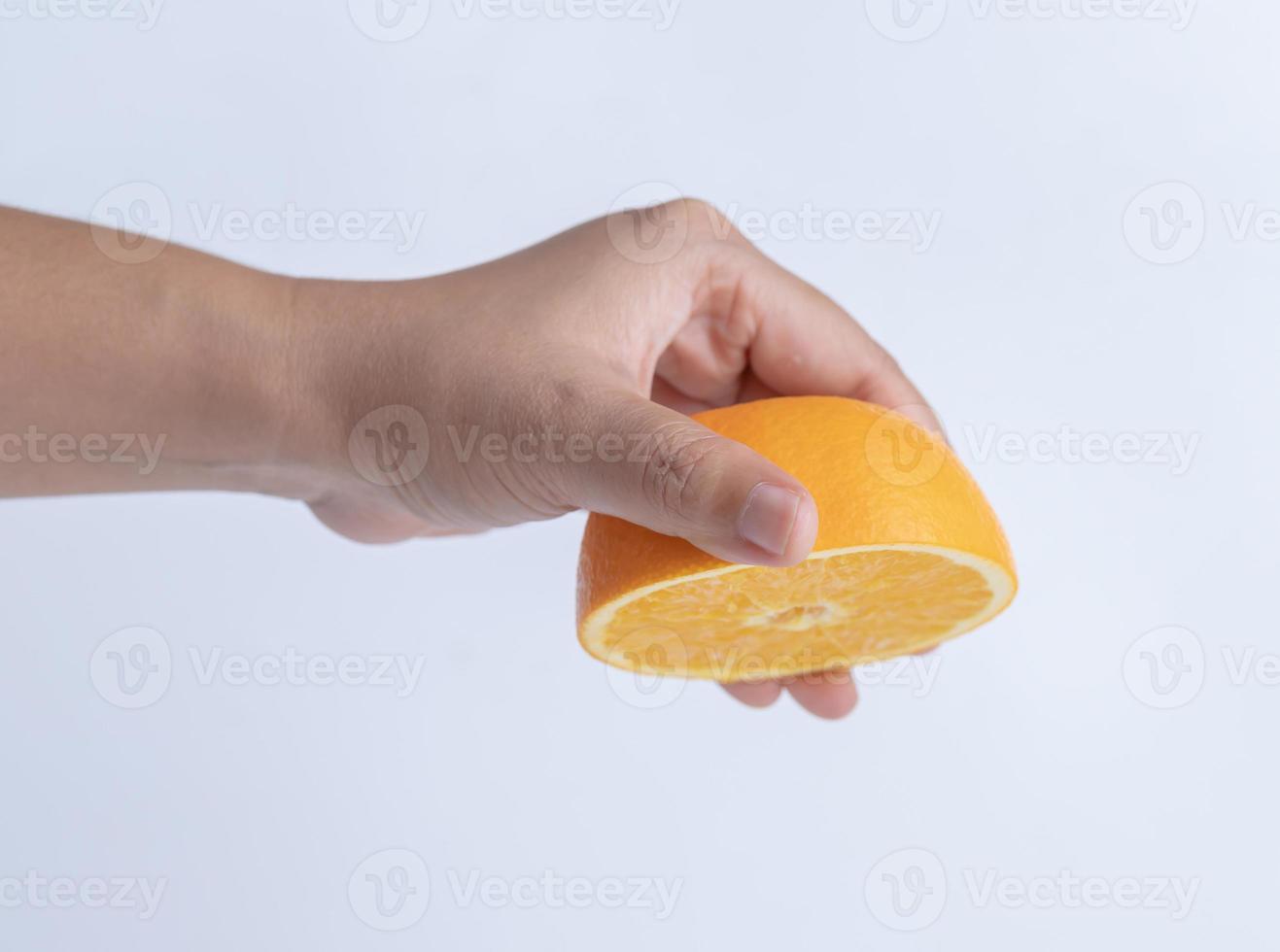 mano exprimiendo una fruta de media naranja foto