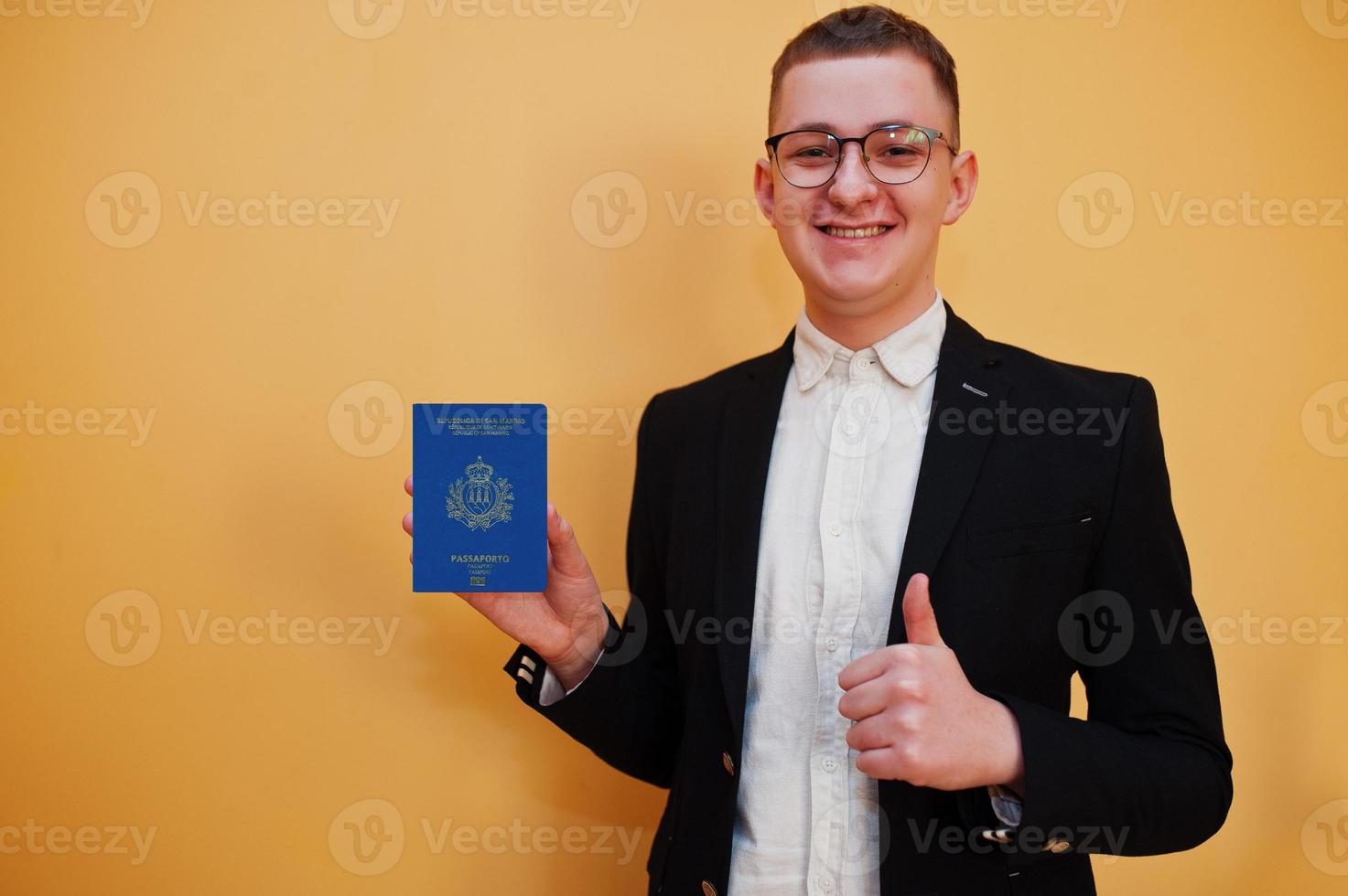 Young handsome man holding Most Serene Republic of San Marino passport id over yellow background, happy and show thumb up. Travel to Europe country concept. photo