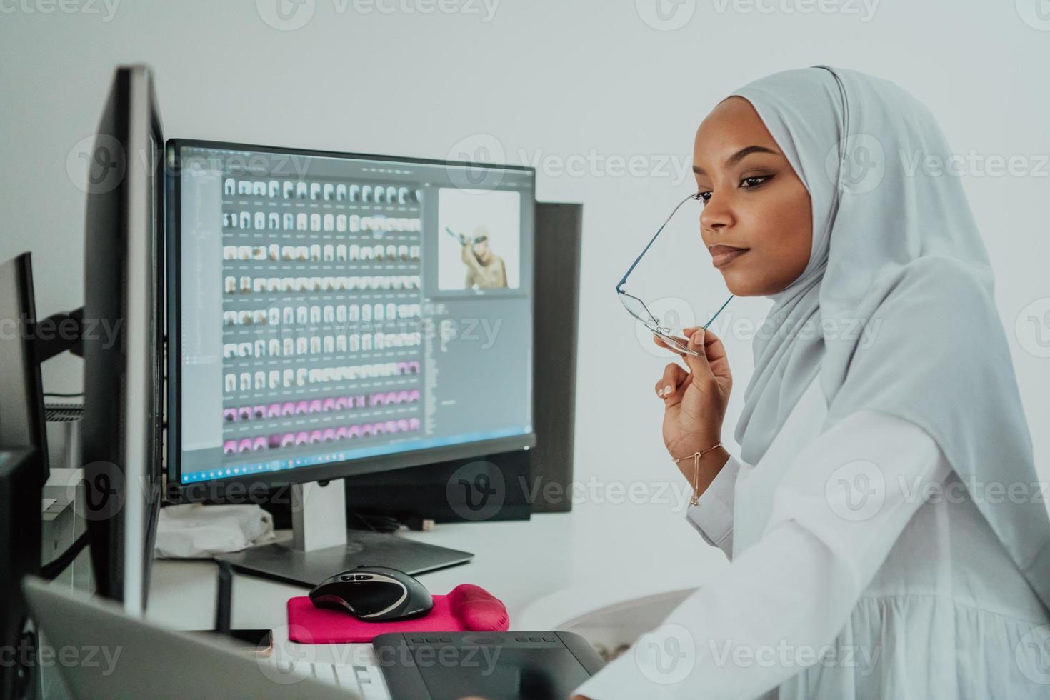 Young Afro-American modern Muslim businesswoman wearing a scarf in a creative bright office workplace with a big screen. photo