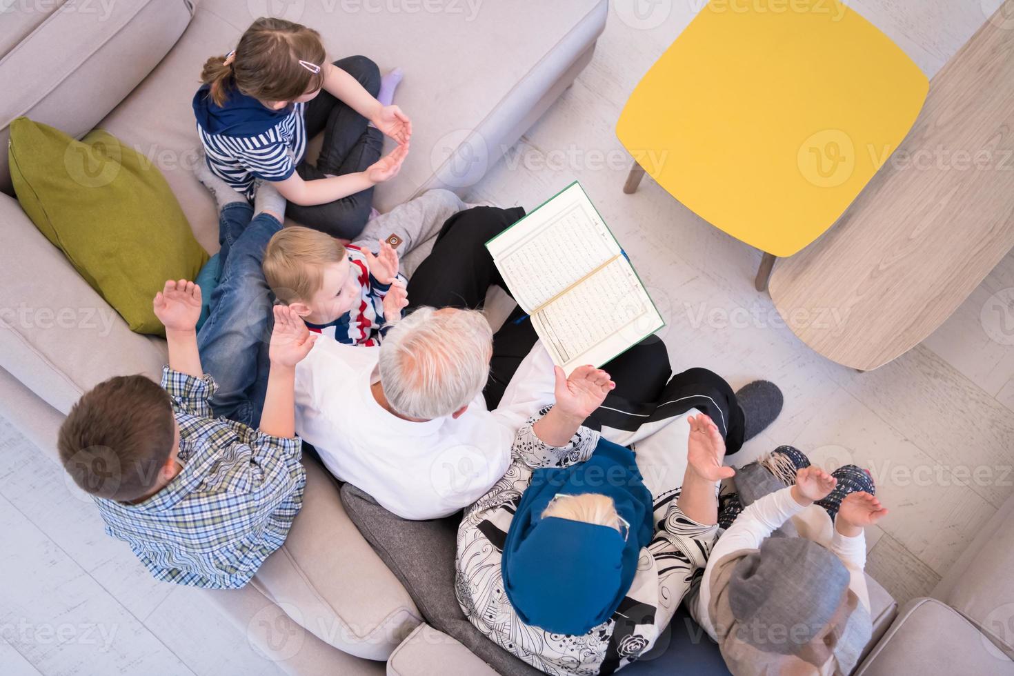 top view of modern muslim grandparents with grandchildren reading Quran photo