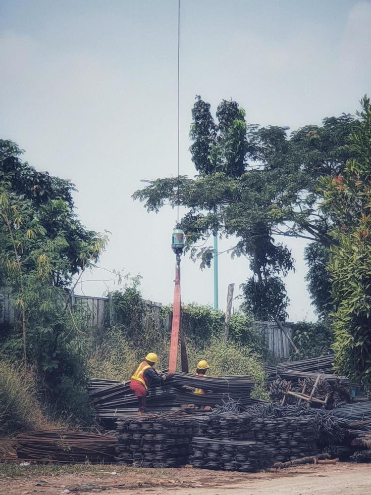 Two construction workers are mobilizing pieces of structural steel. This process is carried out with the help of cranes and slings. photo