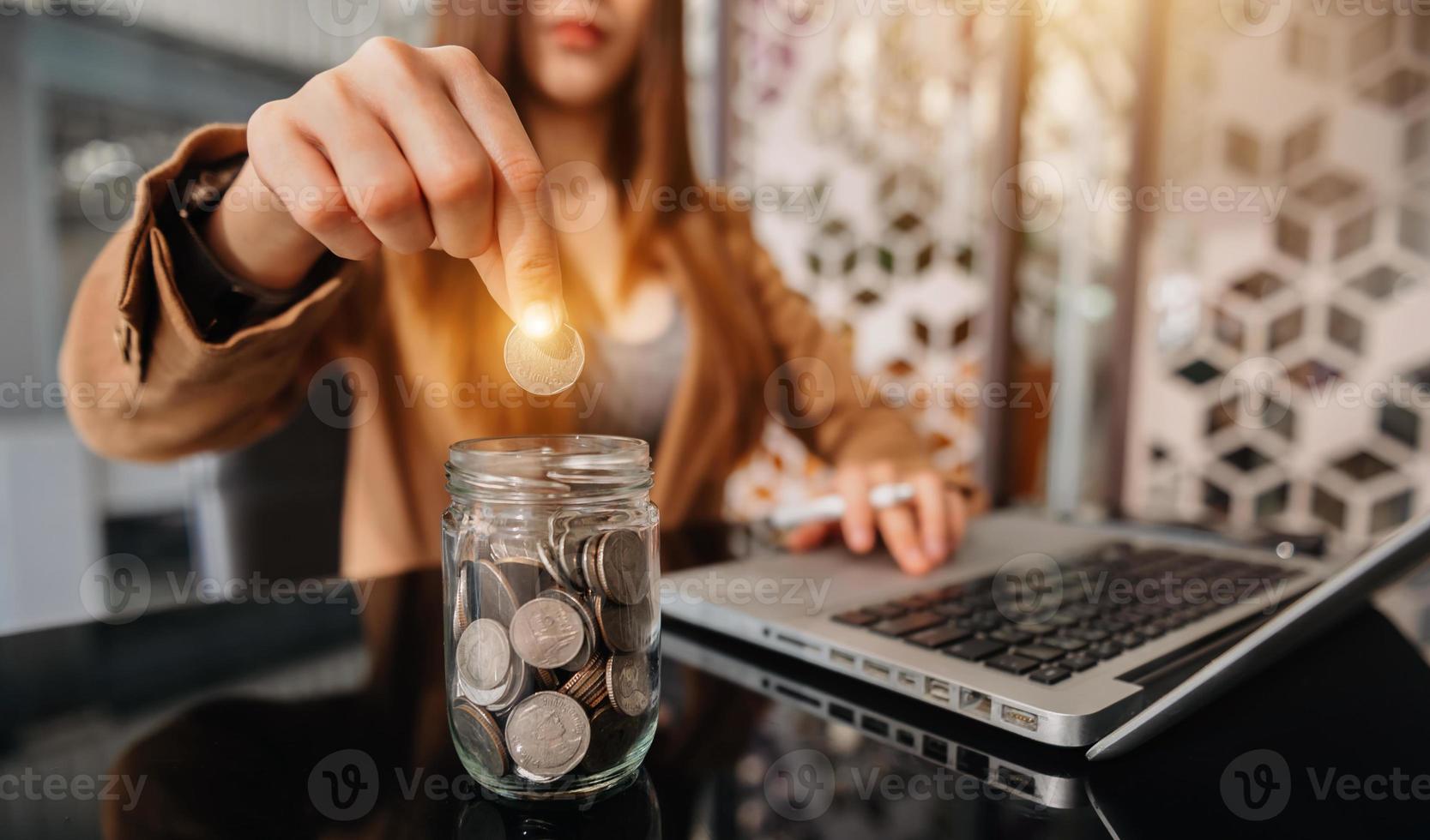 Hand putting mix coins and seed in clear bottle and business investment growth concept at modern office photo