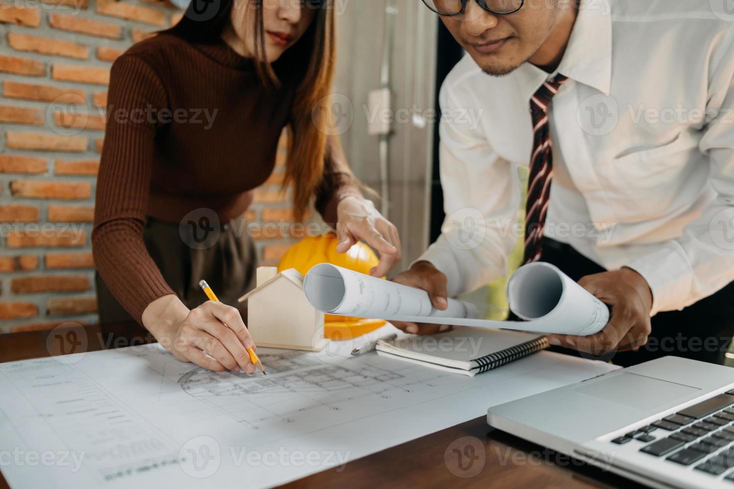 Two colleagues discussing data working and tablet, laptop with on on architectural project at construction site at desk in office photo