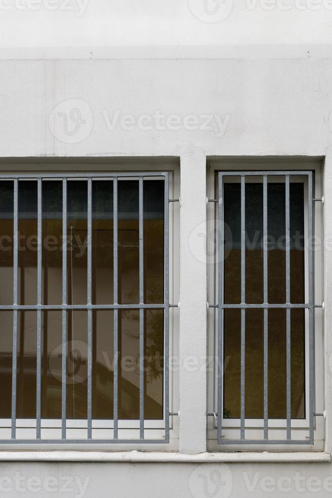 barred window on white house wall photo