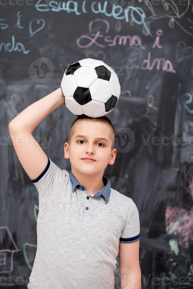 happy boy holding a soccer ball on his head photo