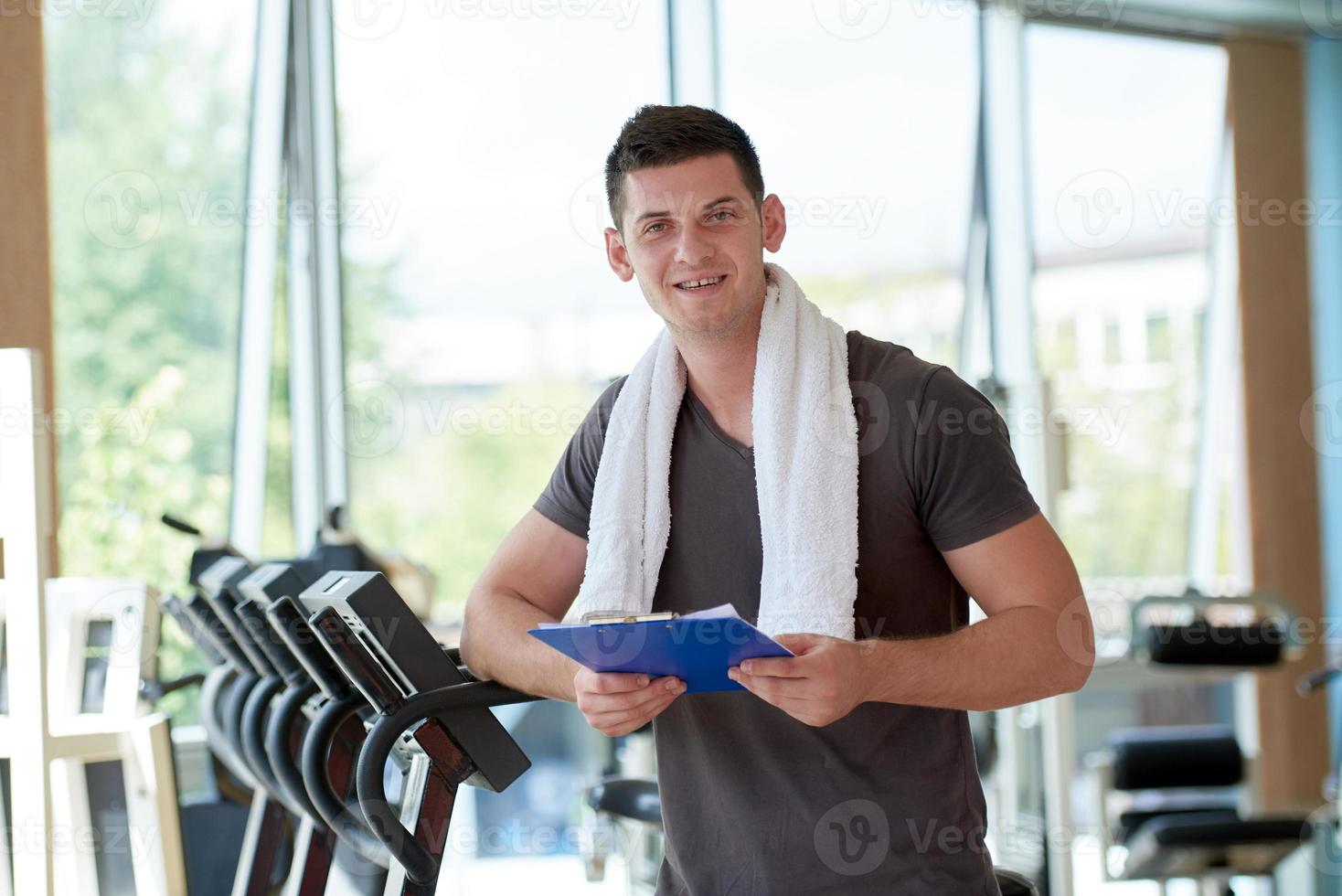 trainer with clipboard standing in a bright gym photo