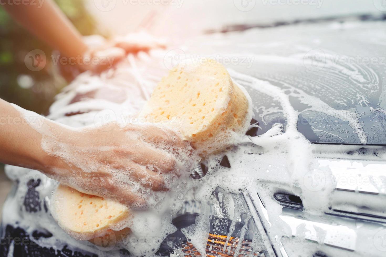 people worker man holding hand yellow sponge and bubble foam cleanser window for washing car. Concept car wash clean. Leave space for writing messages. photo