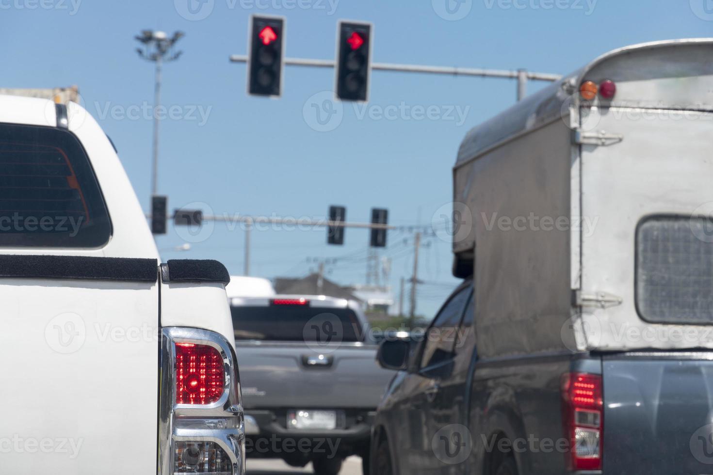 la parte trasera del camión blanco se detiene en la carretera con la luz de freno encendida. congestión del tráfico durante las horas de trabajo o durante las horas pico. poste de semáforo listo para ir a la señal roja en el frente. foto