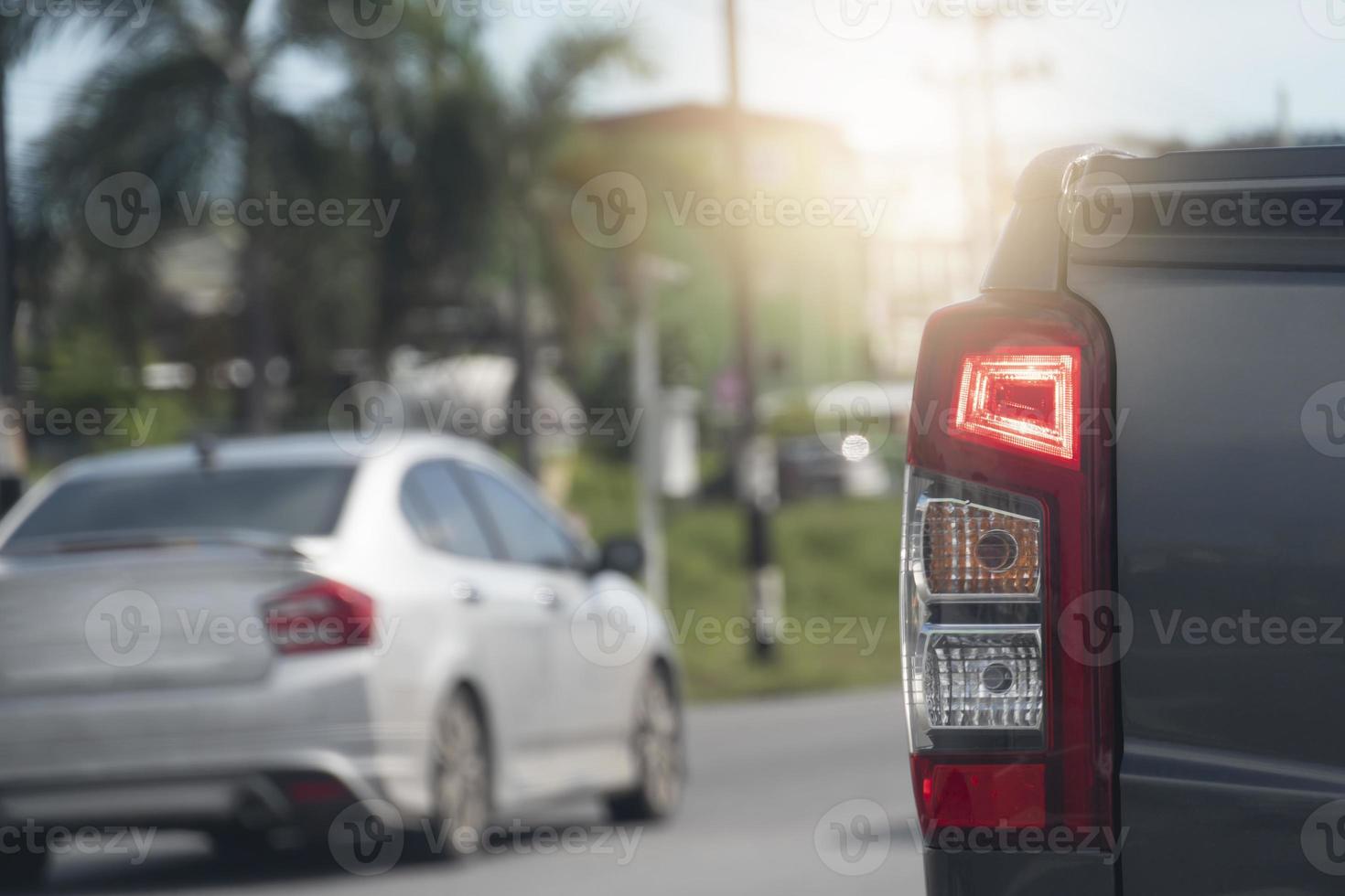 la parte trasera del camión de recogida se detiene en color gris en la carretera con la luz de freno encendida. el fondo y el desenfoque de otros autos se detienen en la ciudad en días. foto