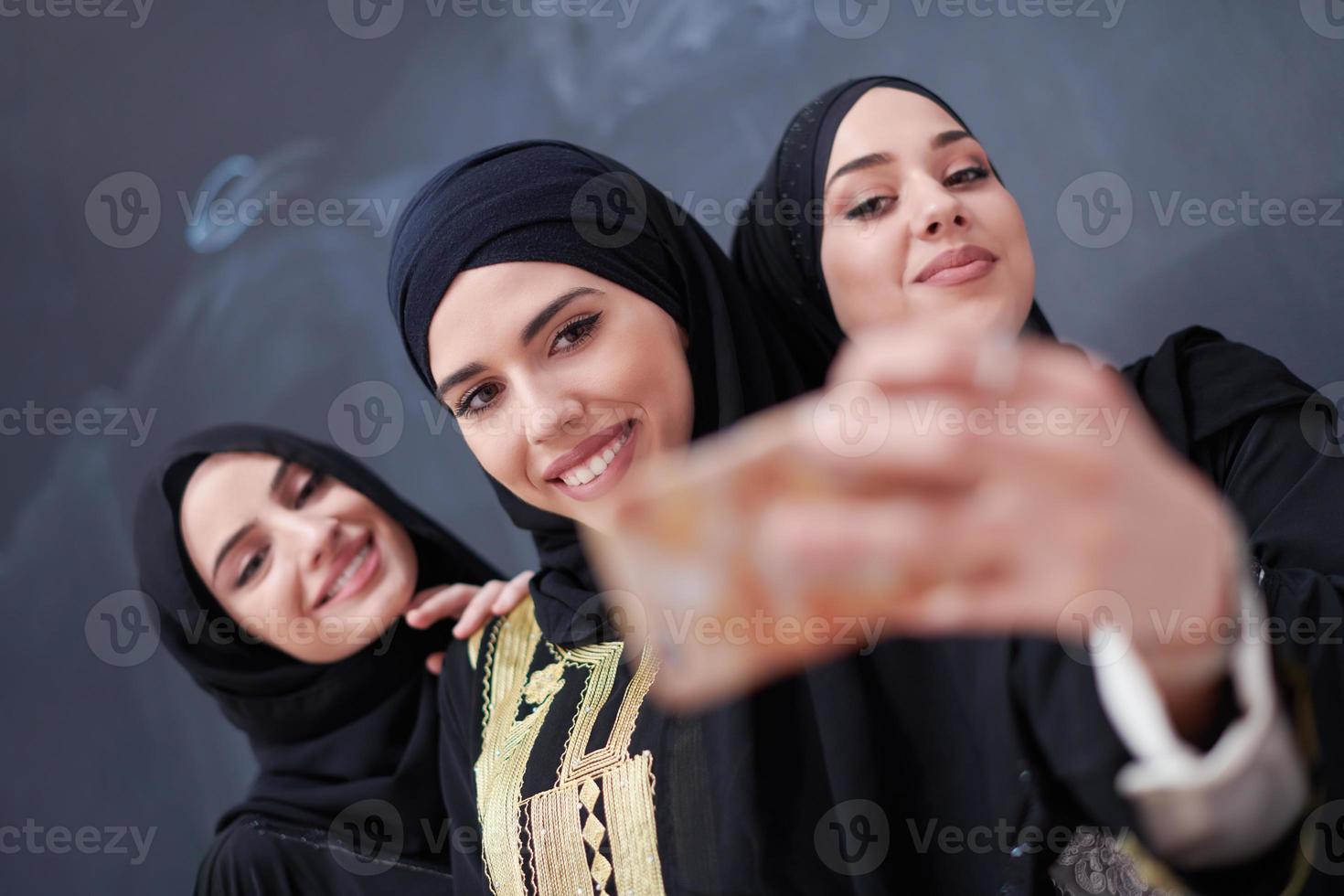 muslim women taking selfie picture in front of black chalkboard photo