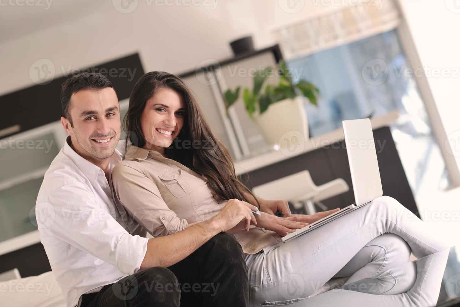 una pareja alegre se relaja y trabaja en una computadora portátil en una casa moderna foto