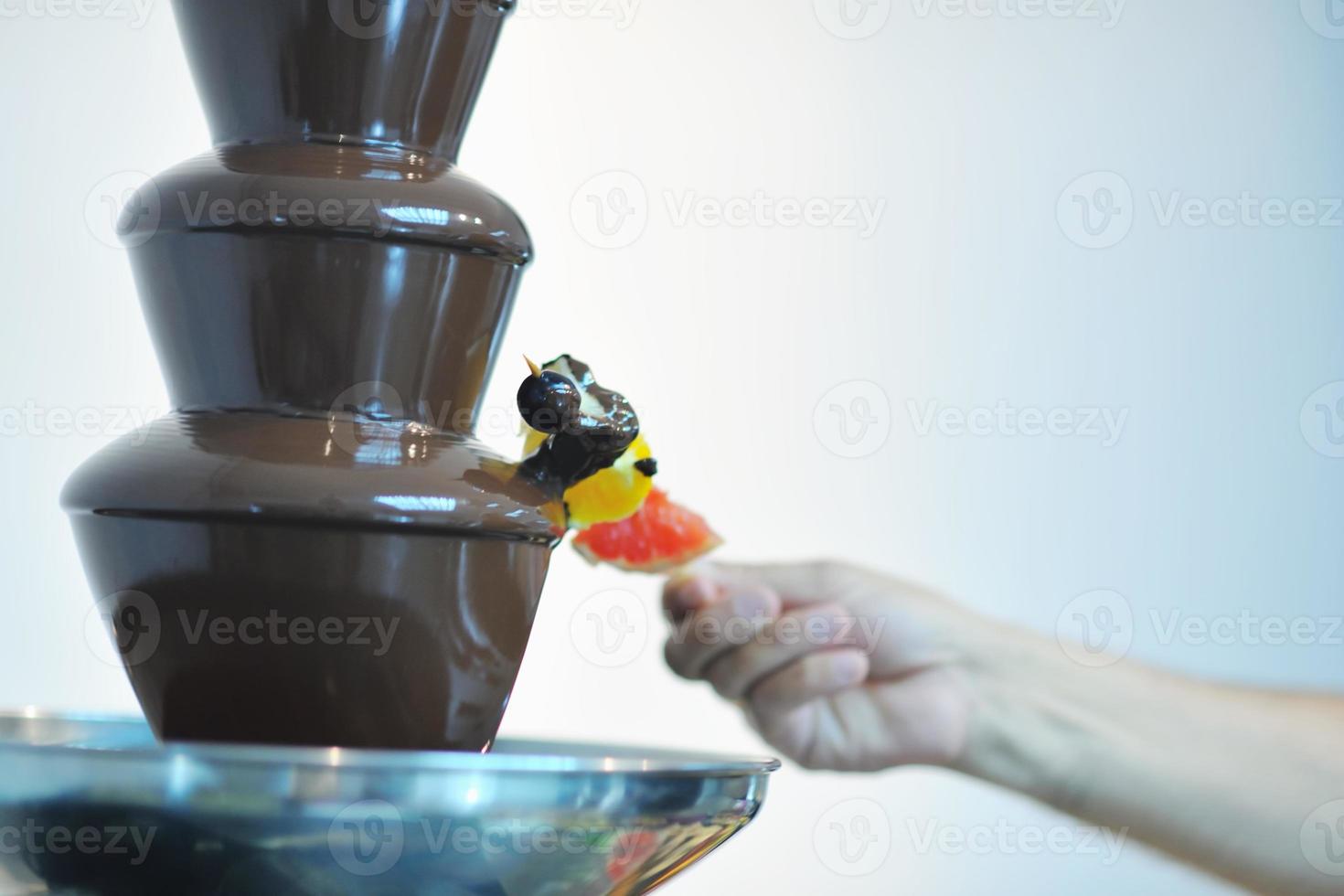 liquid chocolate fountain and fresh fruits on stick photo