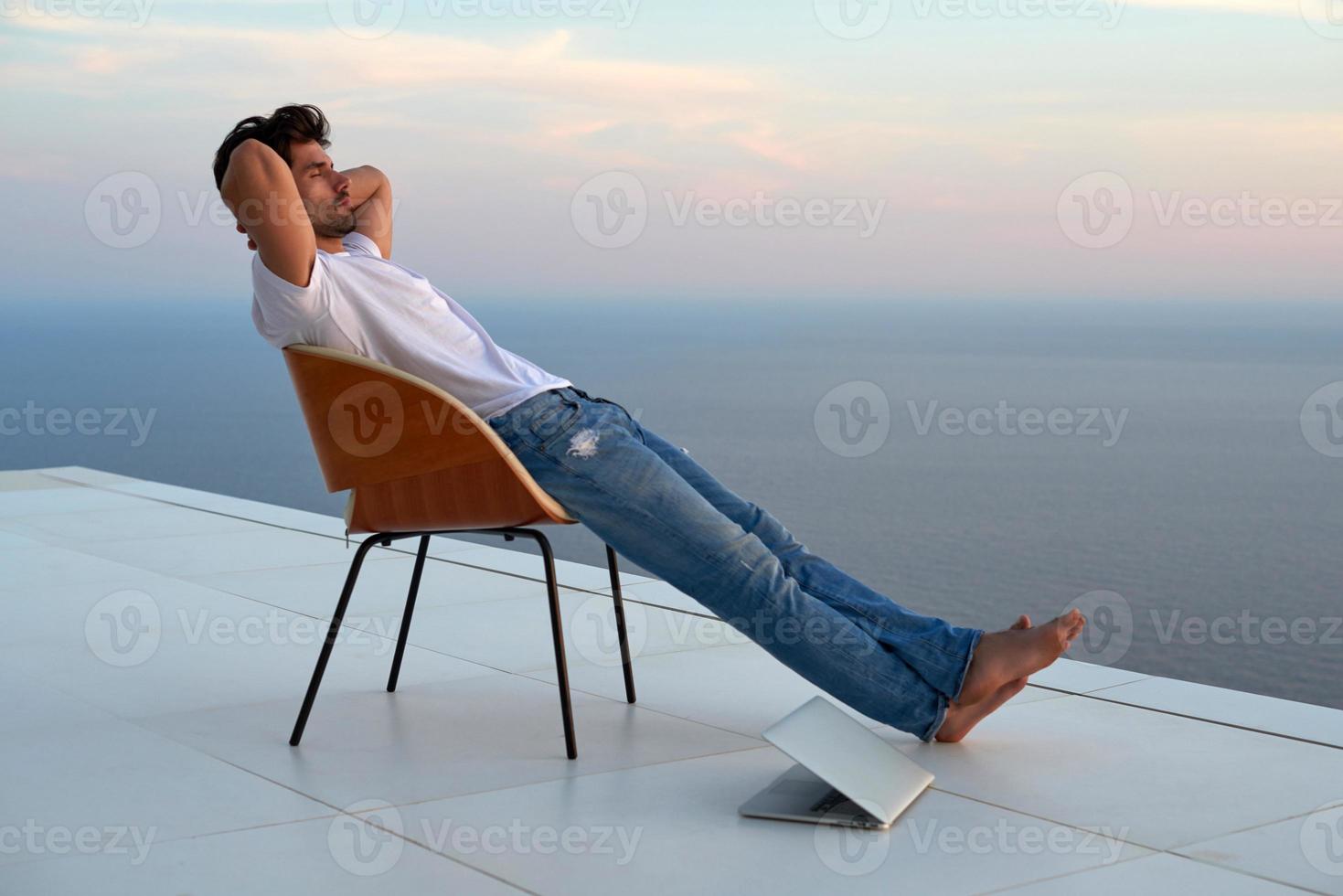 relaxed young man at home on balcony photo