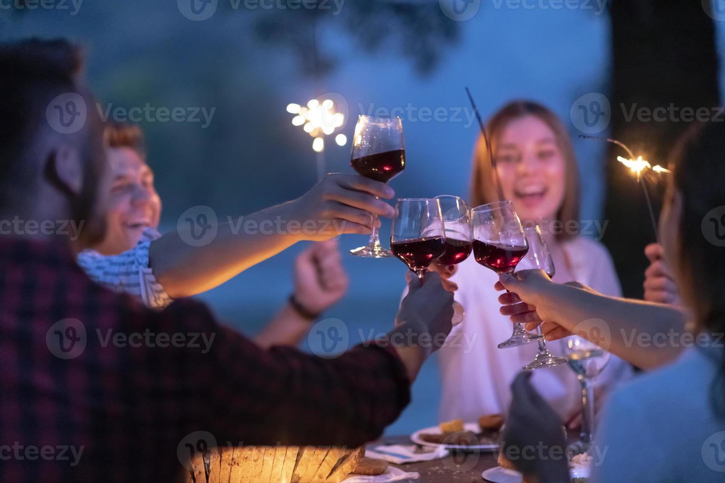 friends toasting red wine glass while having picnic french dinner party outdoor photo