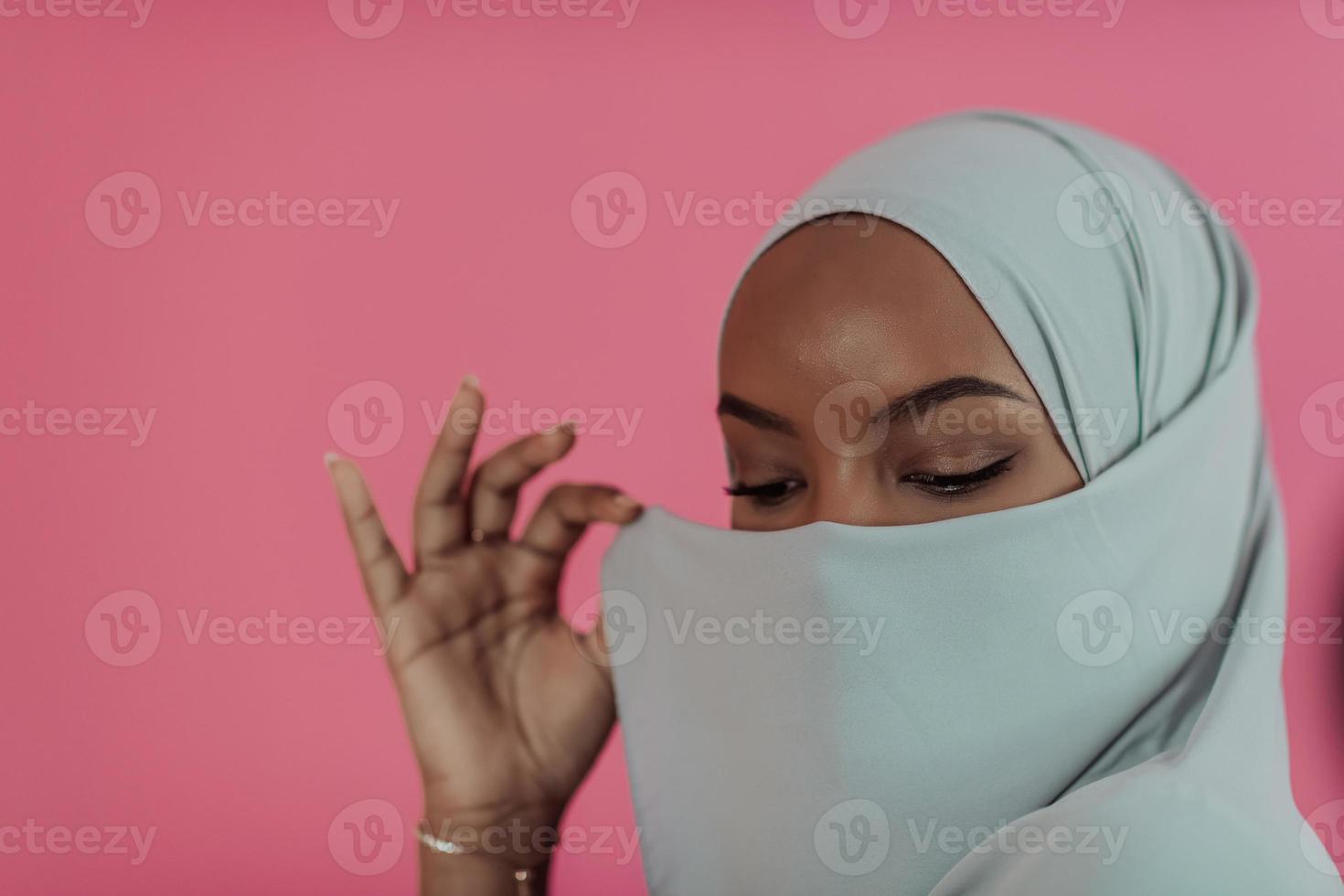 Portrait of young modern muslim beauty wearing traditional islamic clothes on plastic pink background. Selective focus photo