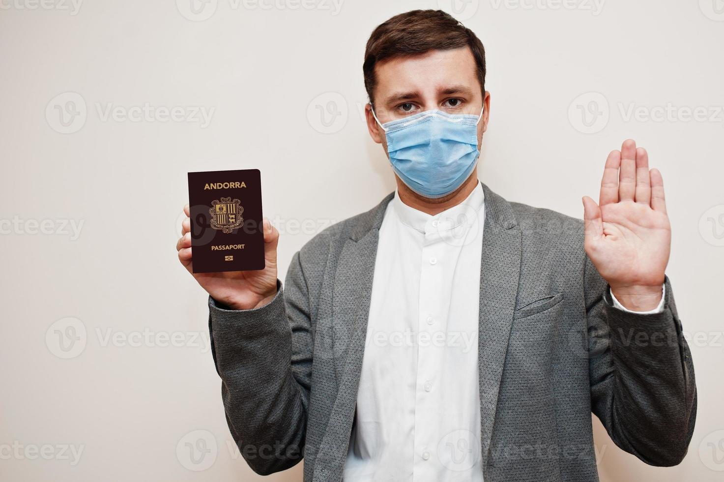 hombre europeo con ropa formal y máscara facial, muestre el pasaporte de andorra con la mano de la señal de stop. bloqueo de coronavirus en el concepto de país de europa. foto