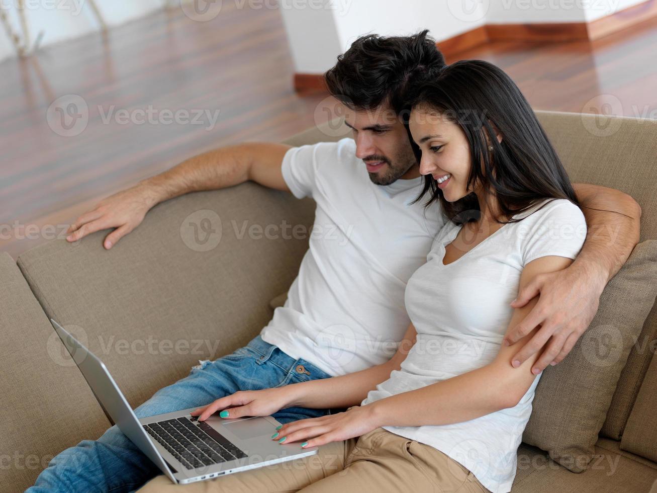 relaxed young couple working on laptop computer at home photo