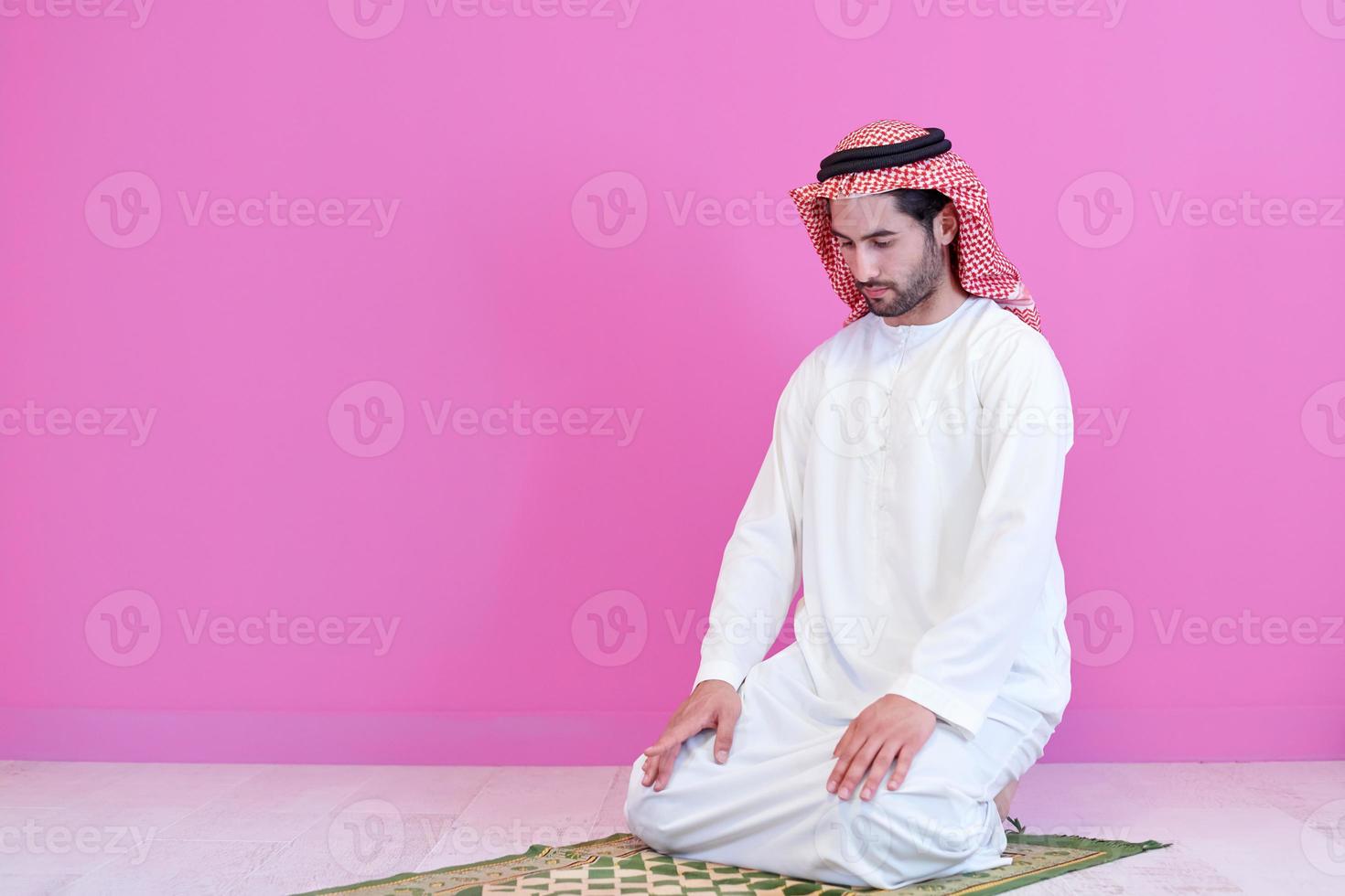 young arabian muslim man praying on the floor at home photo