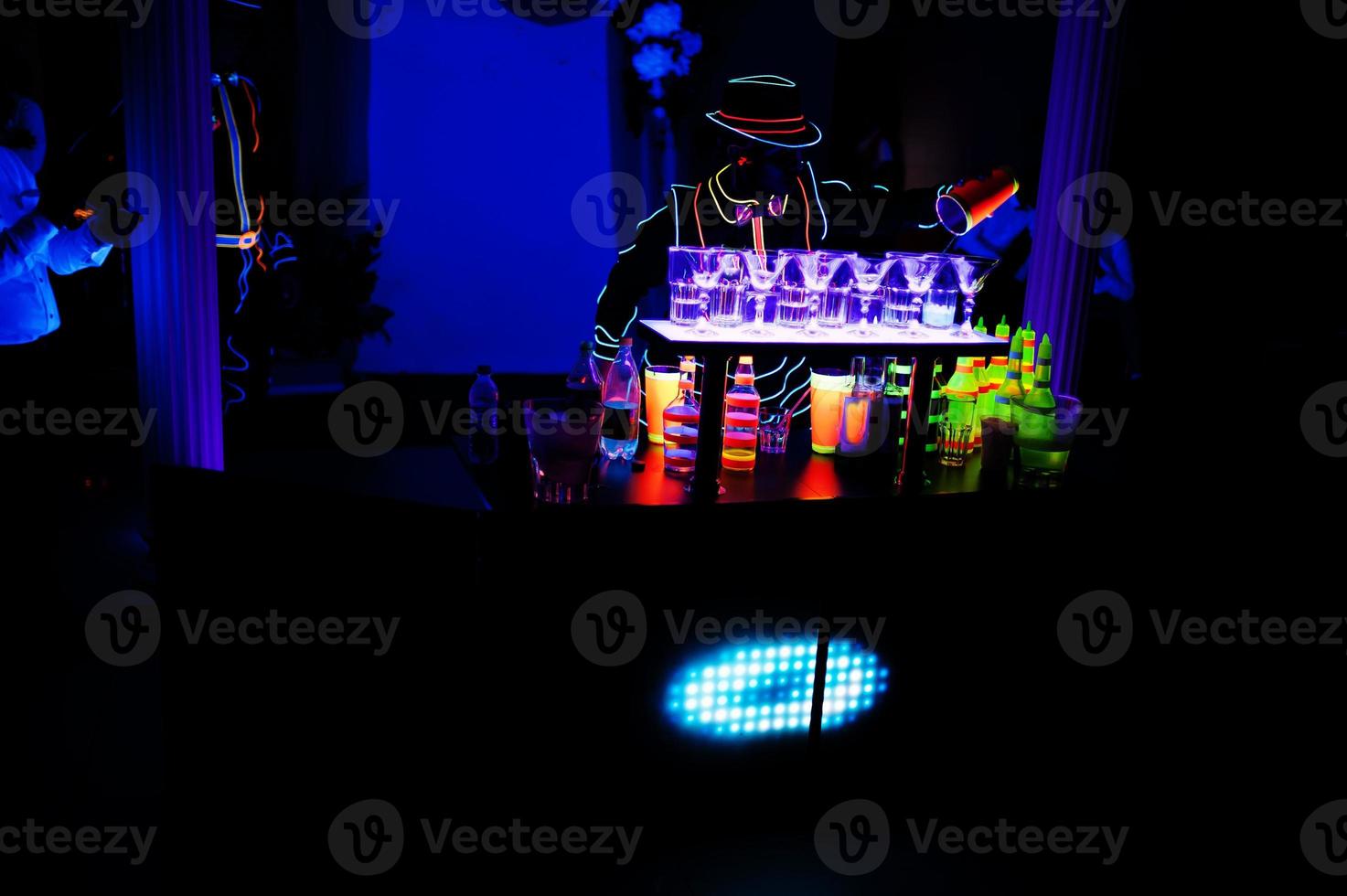 Professional barman and led light show. Silhouette of modern bartender shaking drink at night cocktail bar. photo