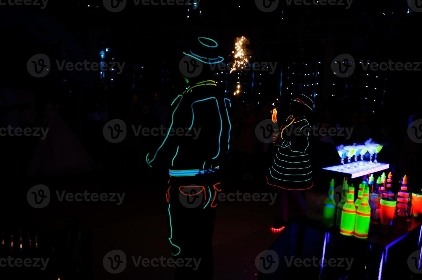 Professional barman and led light fire show. Silhouette of modern bartender shaking drink at night cocktail bar. photo