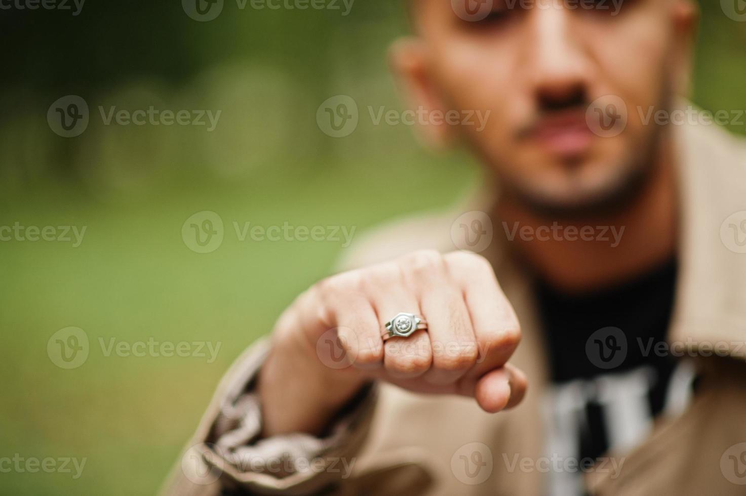 Stylish kuwaiti man at trench coat shows a ring on his hand. photo