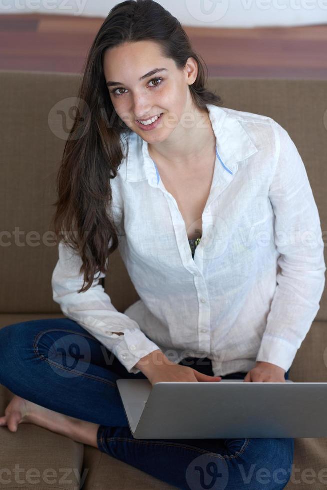 relaxed young woman at home working on laptop computer photo