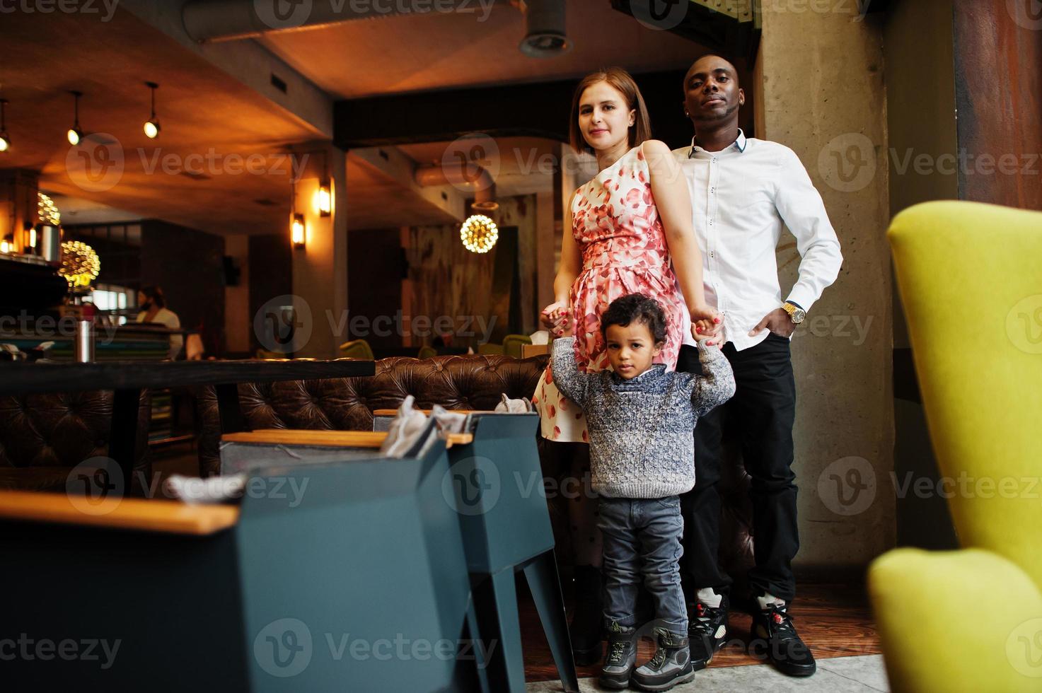 Happy multiethnic family with boy kid spend time at restaurant. Relationships of african man and white european woman. photo