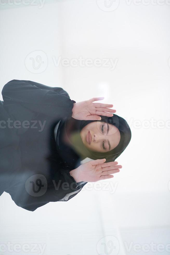 young arabian muslim woman praying on the glass floor at home photo