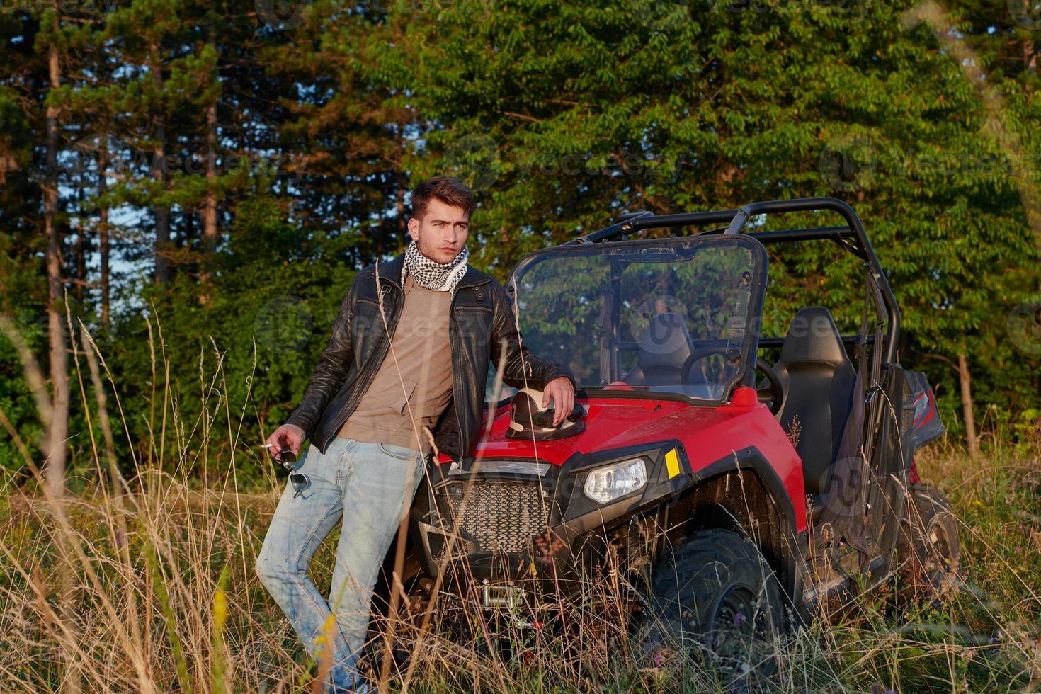 man enjoying beautiful sunny day smoking a cigarette while taking a break from driving a off road buggy car photo