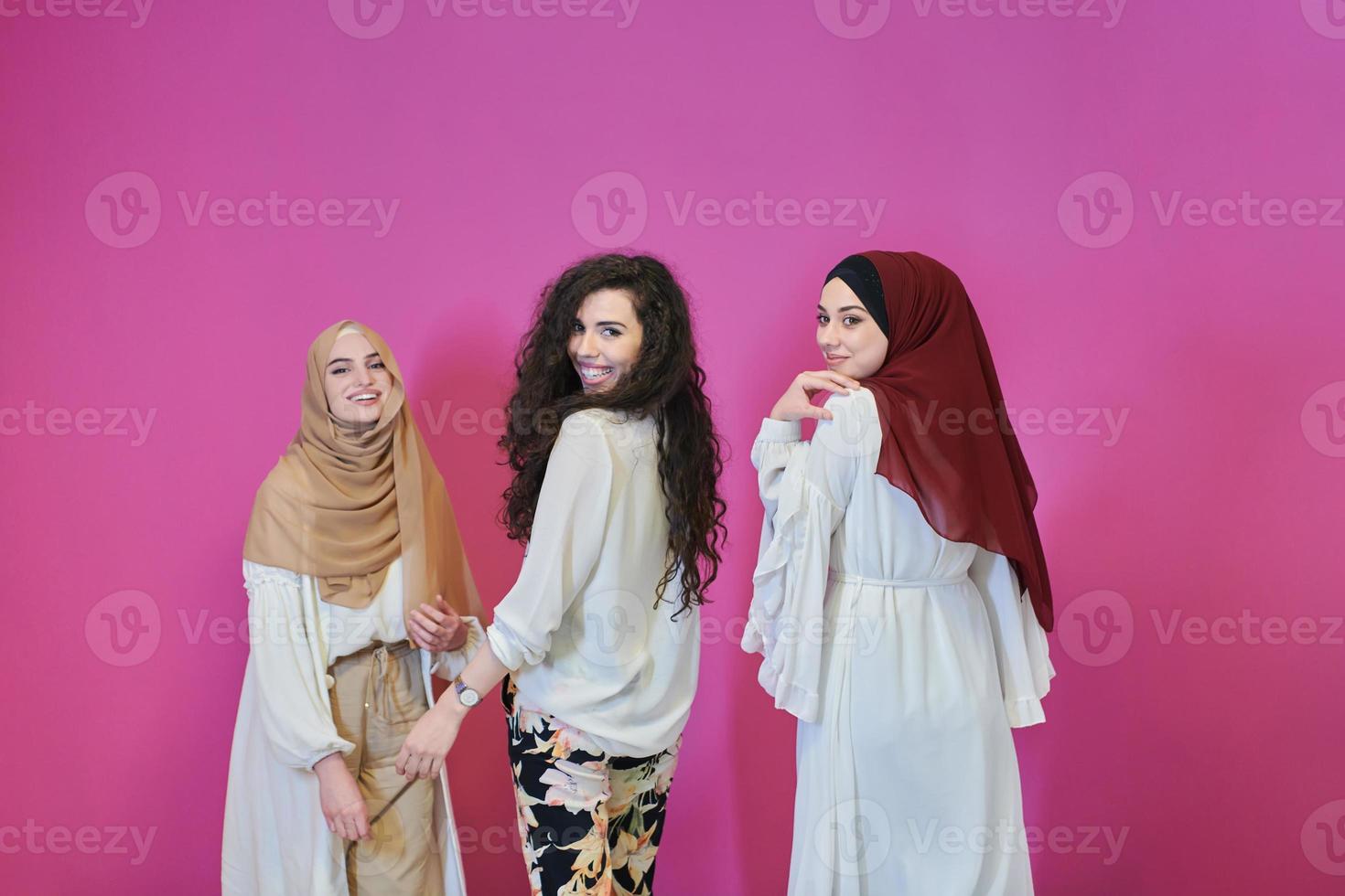 Young muslim women posing on pink background photo