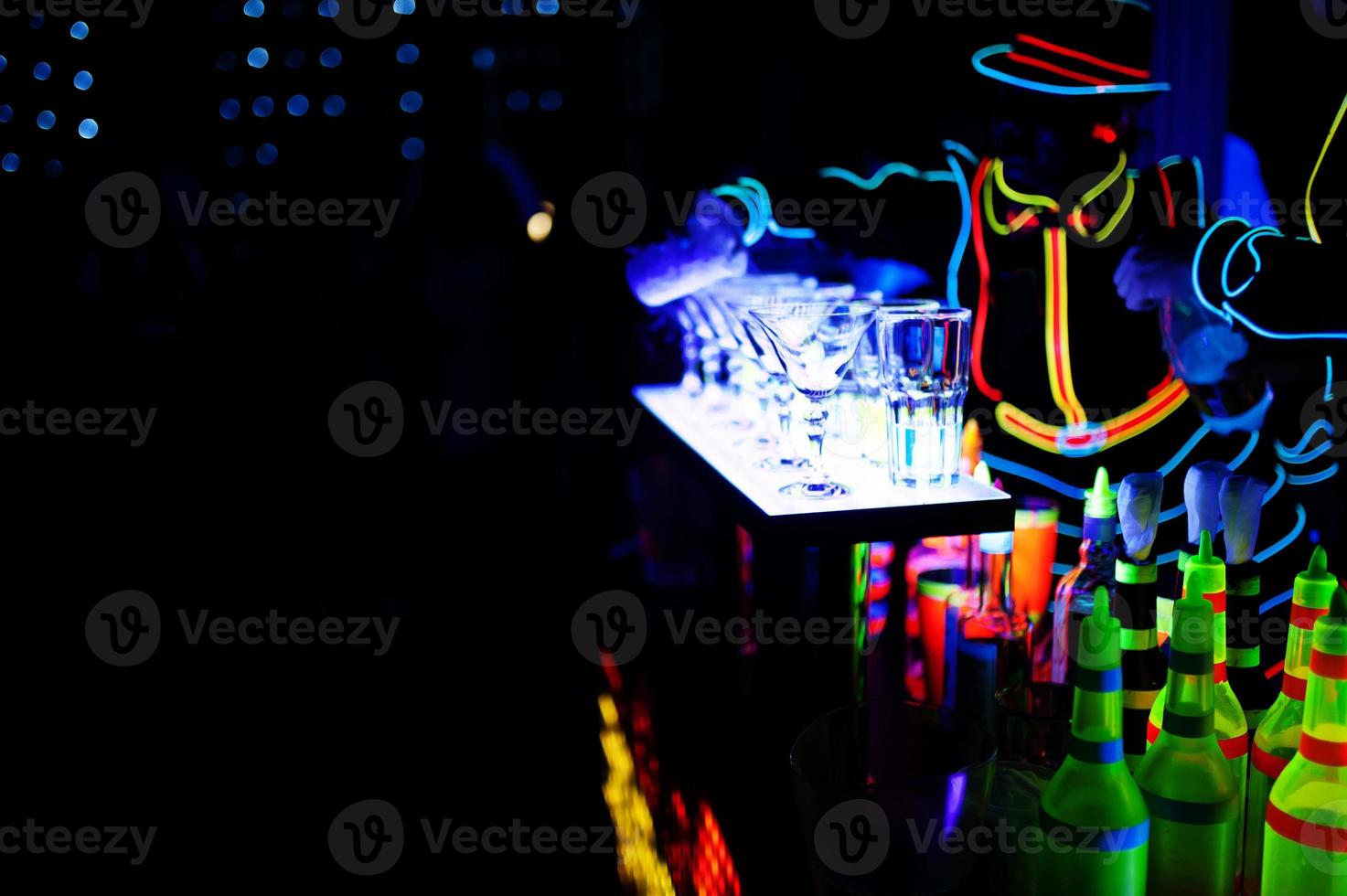 Professional barman and led light show. Silhouette of modern bartender shaking drink at night cocktail bar. photo