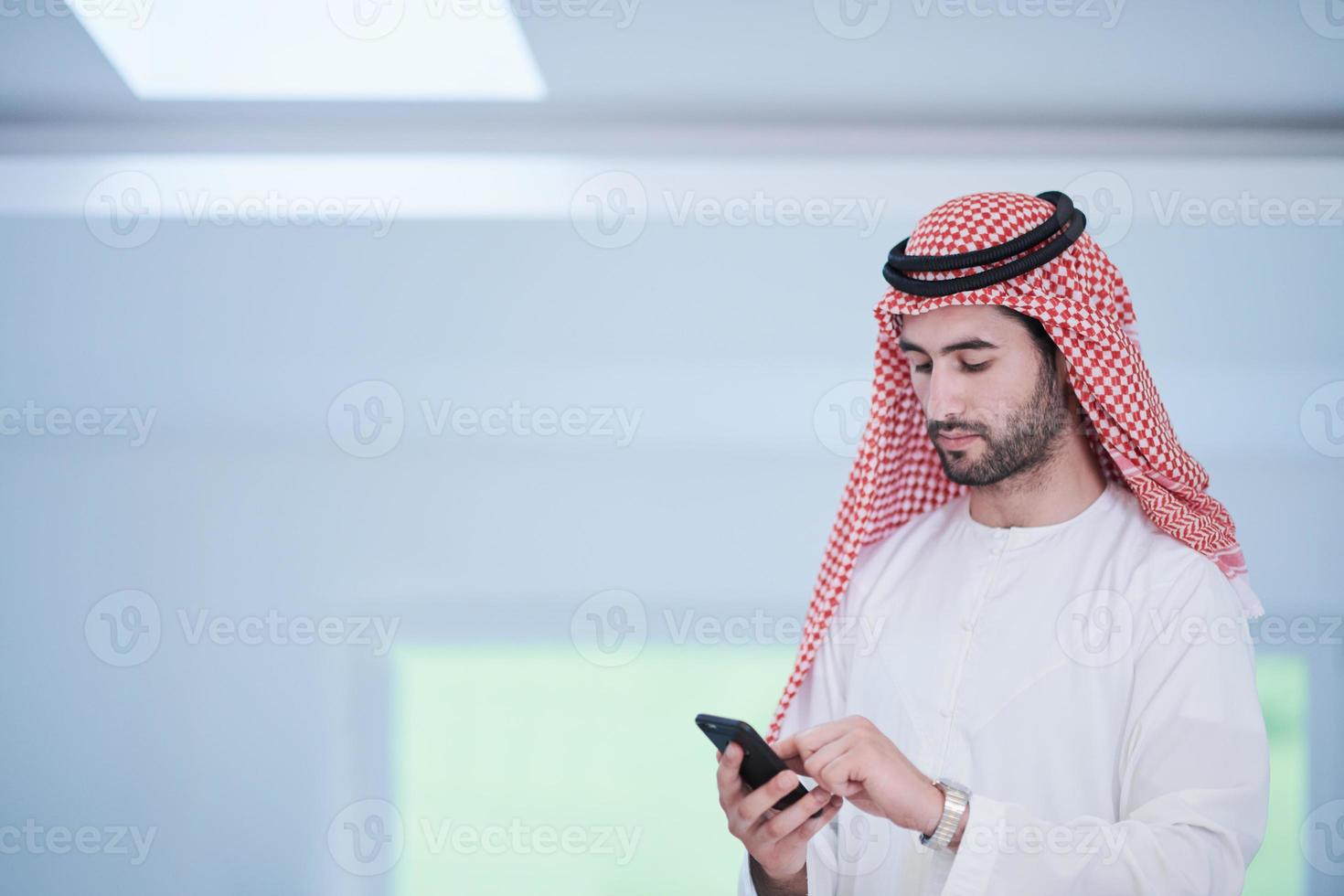 joven hombre de negocios árabe que usa un teléfono inteligente en casa foto