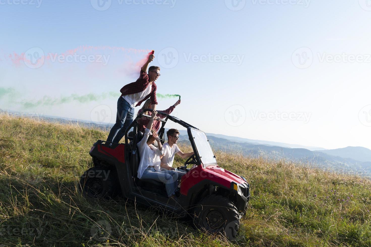 excited people having fun enjoying beautiful sunny day holding colorful torches while driving a off road buggy car photo